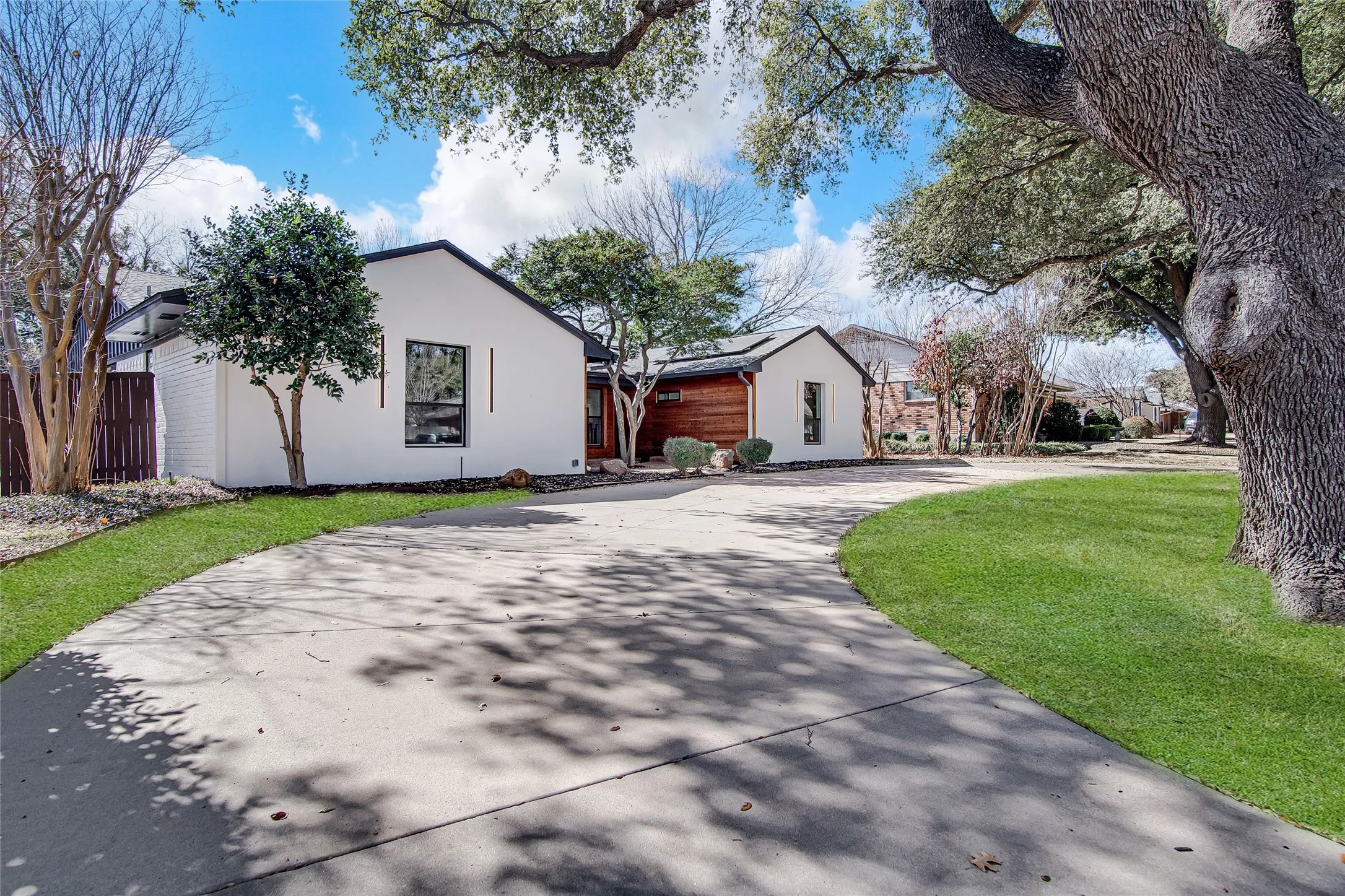 View of front of house with stucco siding, curved driveway, and roof mounted solar panels