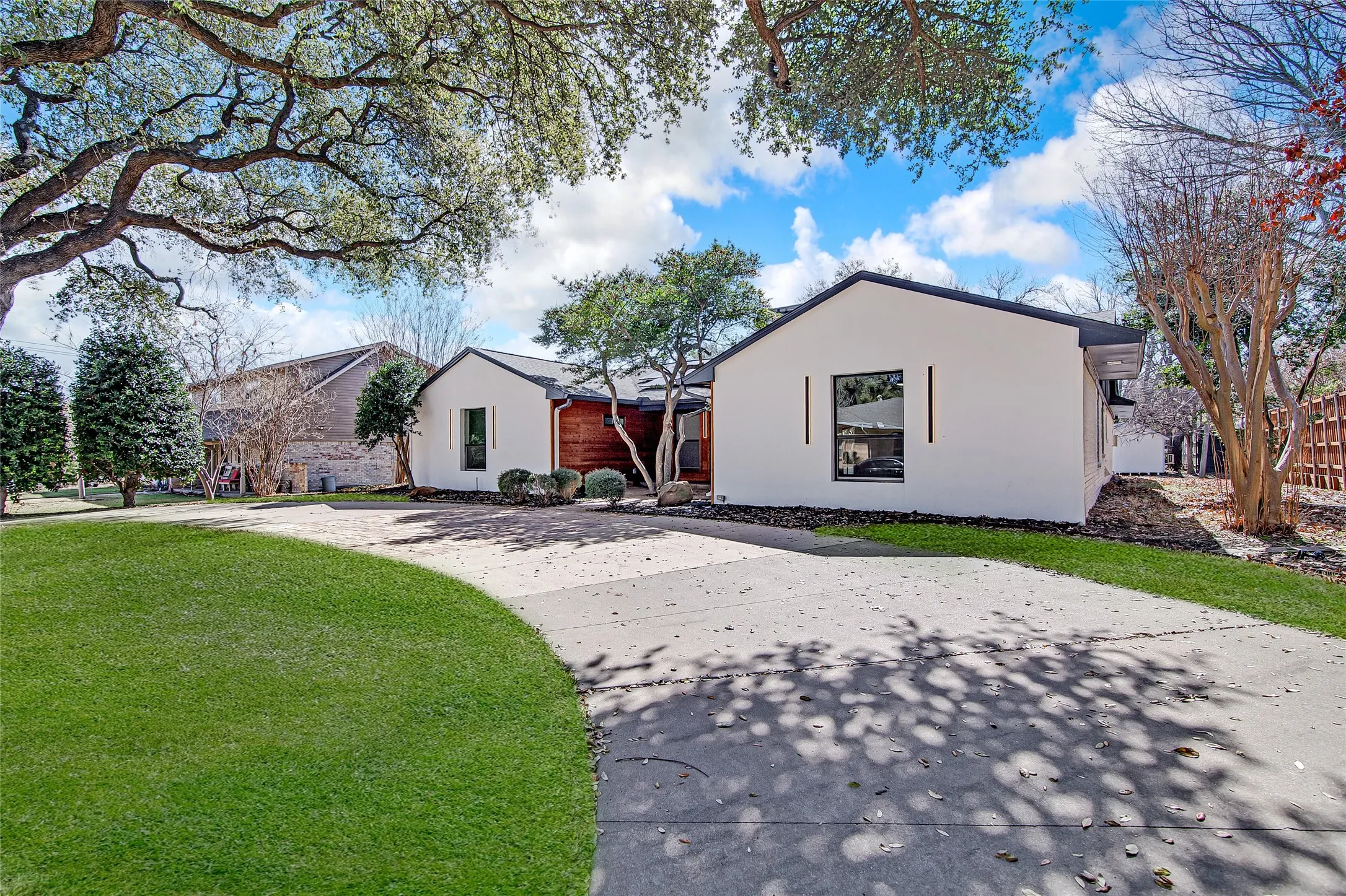 View of front of property with stucco siding, curved driveway, and a front yard