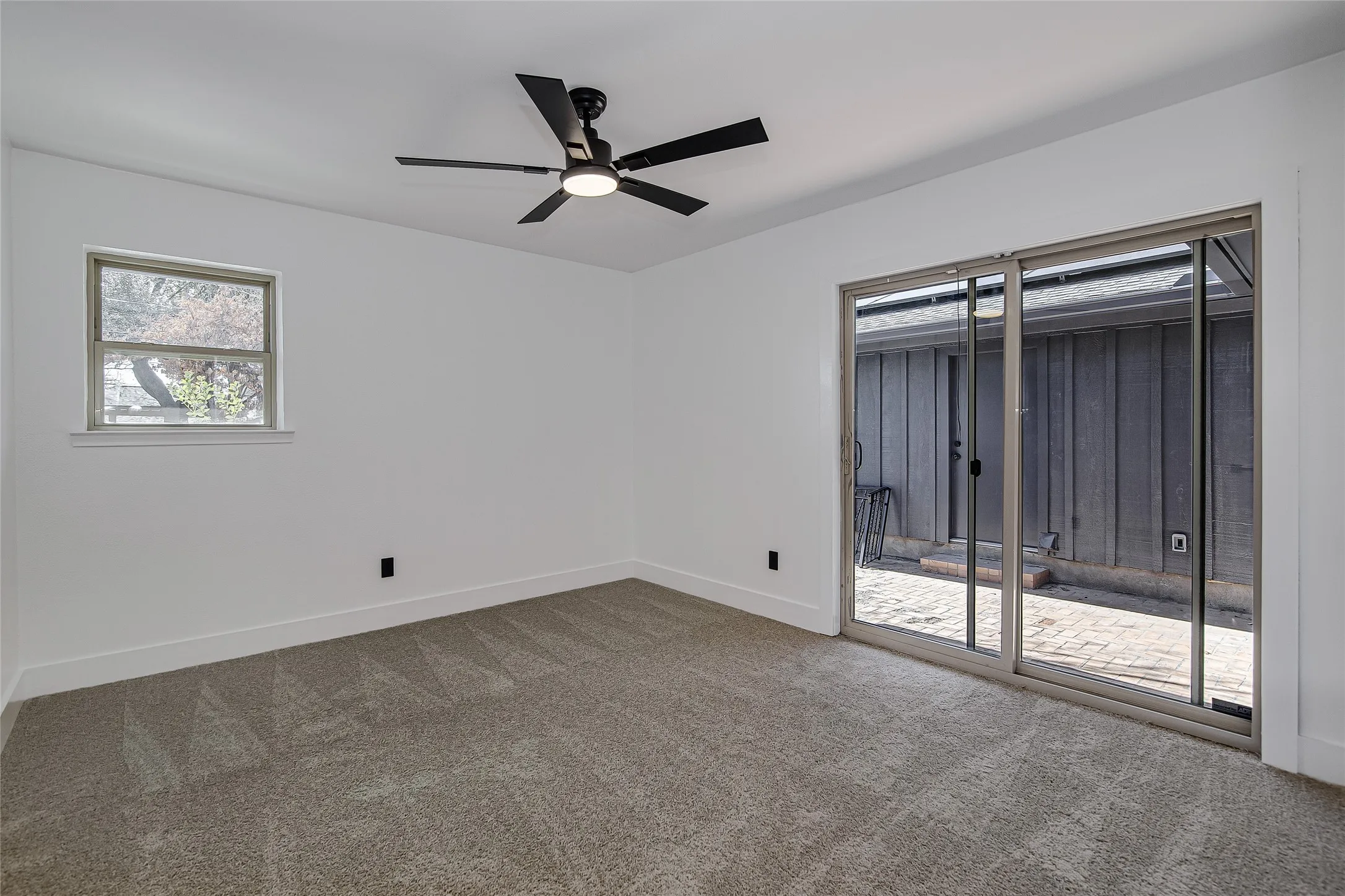Carpeted bedroom #4 featuring baseboards and a ceiling fan and sliding door to exit onto the backyard patio.
