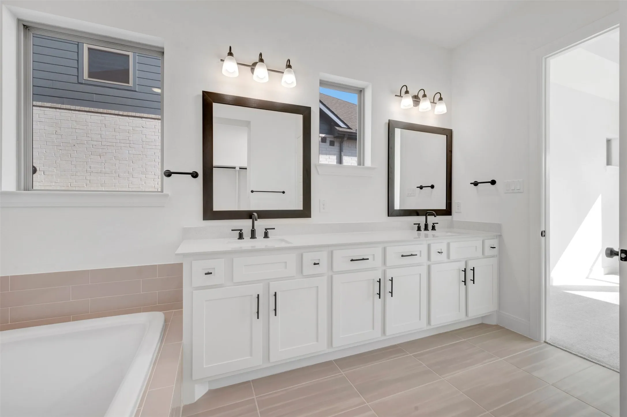 Dual vanity featuring white cabinetry, integrated sinks, and dark framed mirrors