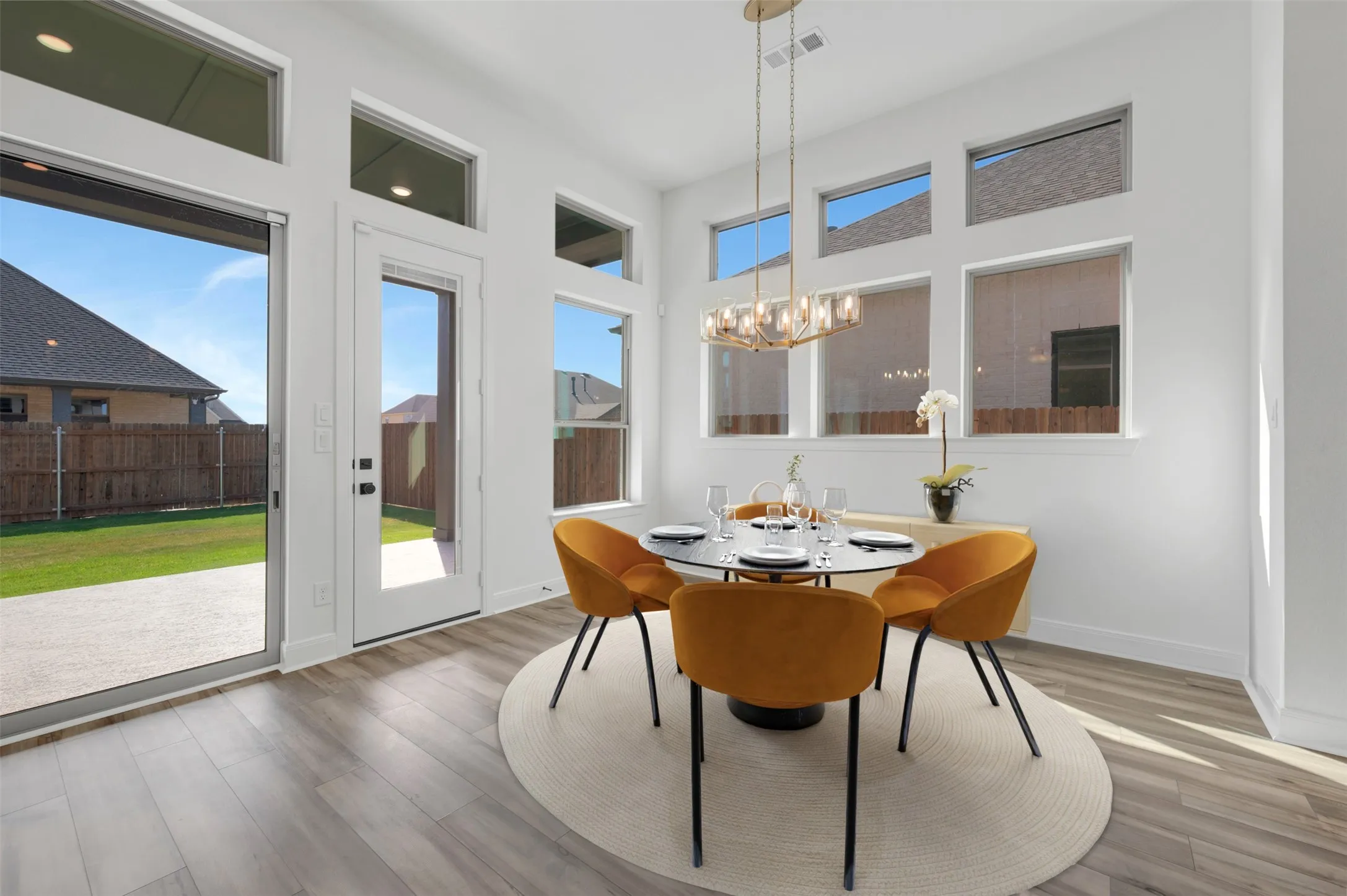 Dining area featuring wood-finish flooring, a contemporary linear chandelier, and expansive windows
