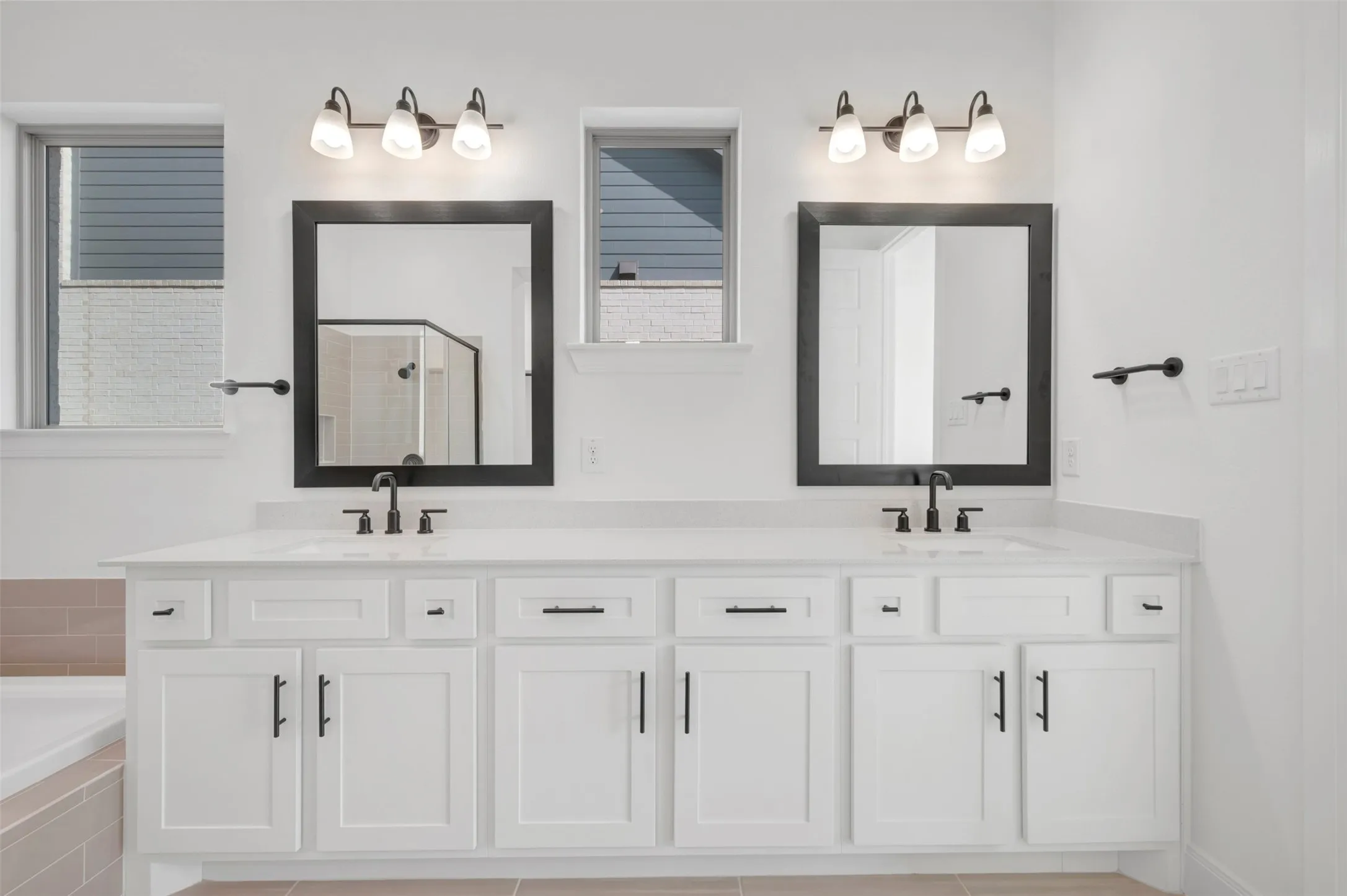 Dual vanity featuring white shaker-style cabinetry, white countertops, and matte black hardware
