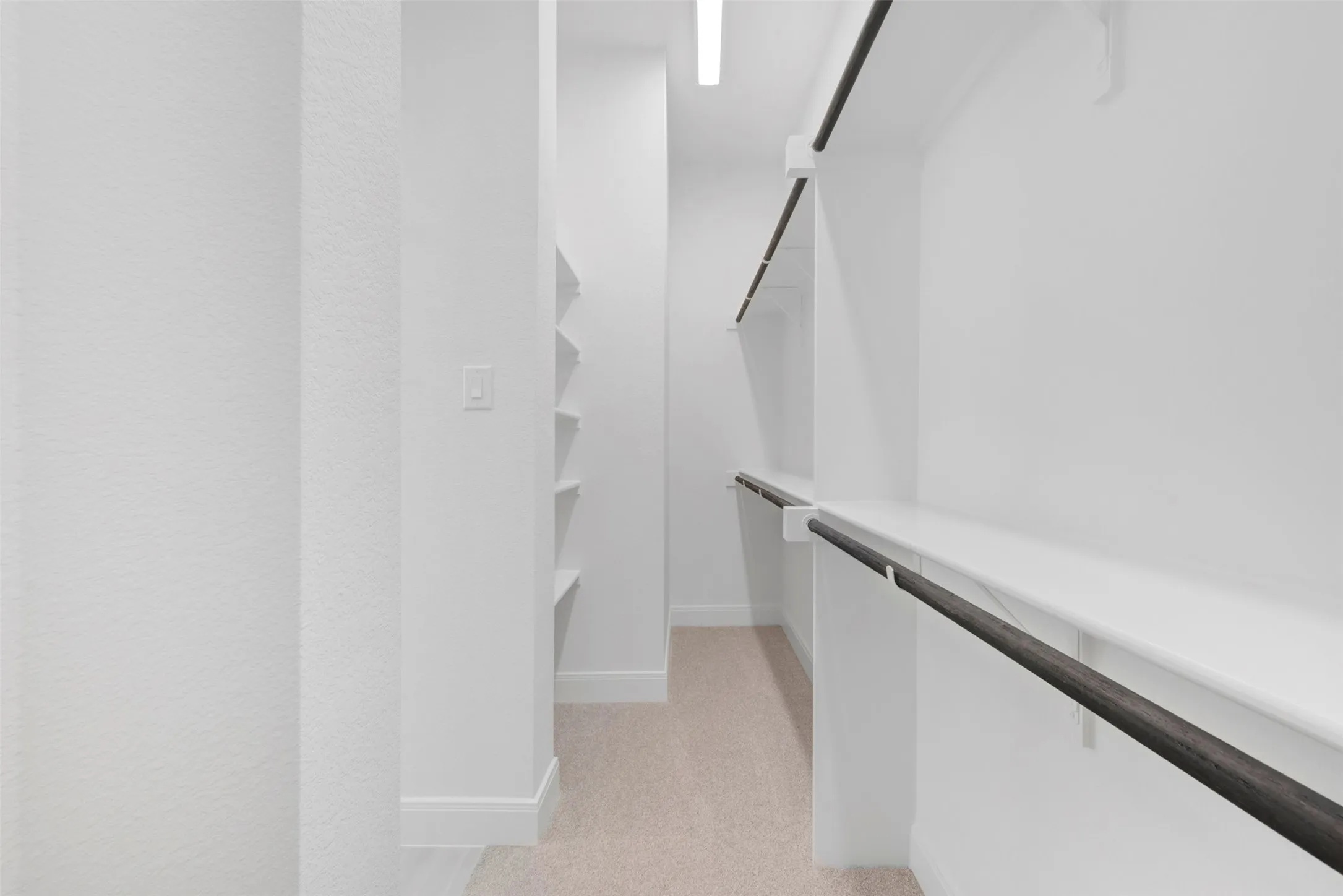 Expansive walk-in closet featuring built-in shelving, two levels of hanging rods, and neutral carpeting