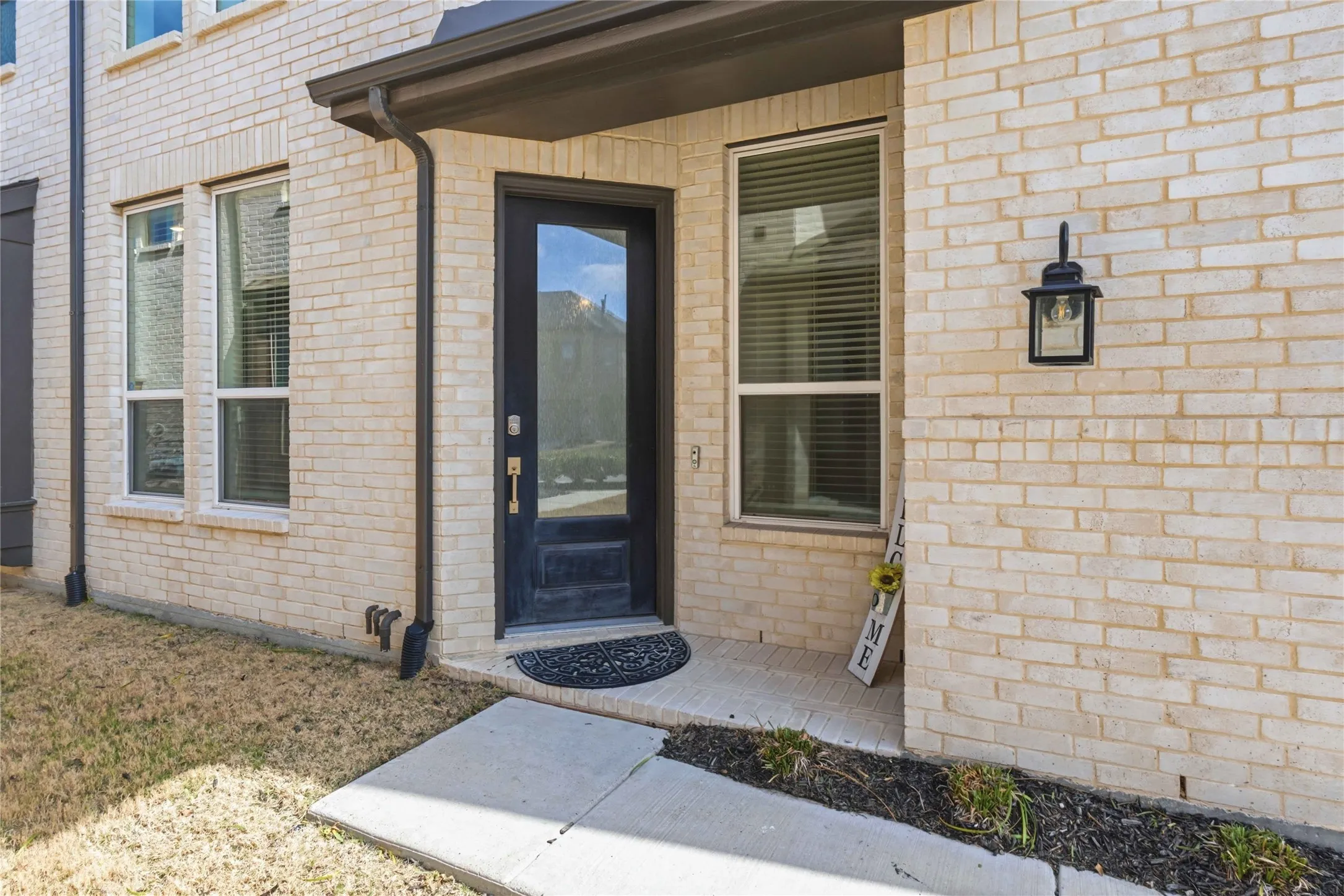 View of exterior entry featuring brick siding and a lawn