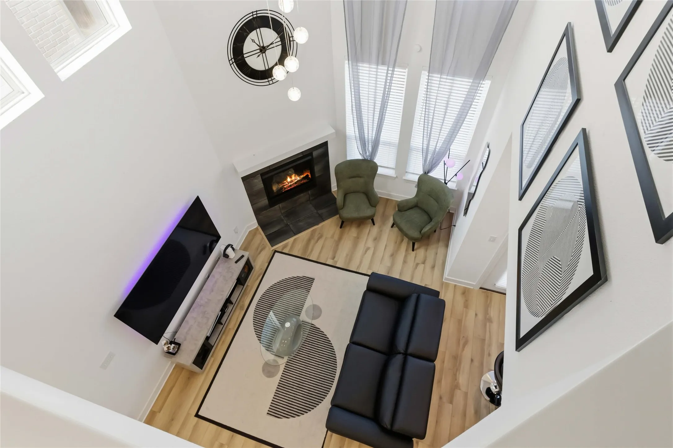 Living area featuring wood finished floors, a glass covered fireplace, and a high ceiling