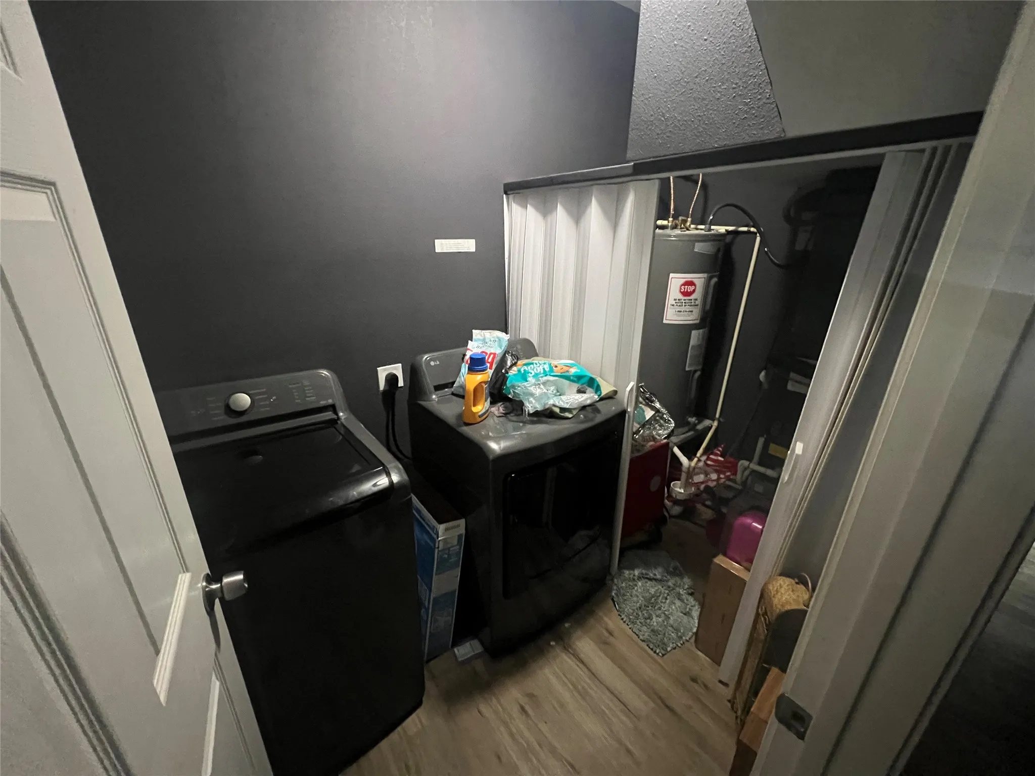 Laundry area featuring light wood-type flooring, electric water heater, and washing machine and clothes dryer