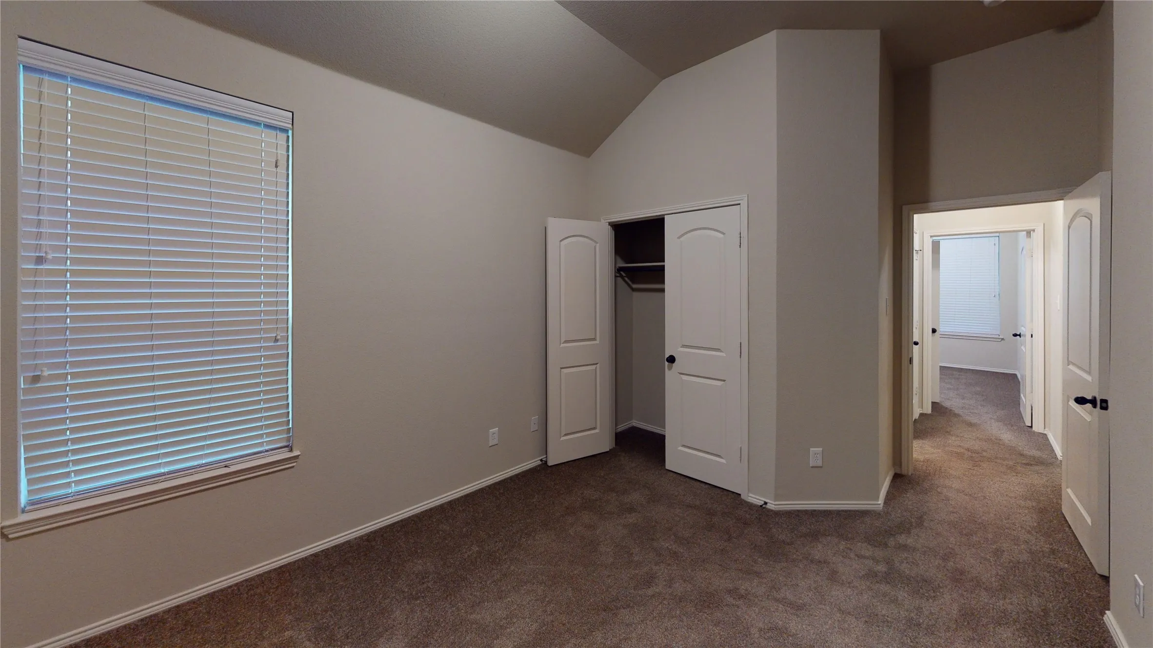 Unfurnished bedroom featuring lofted ceiling, dark carpet, and a closet