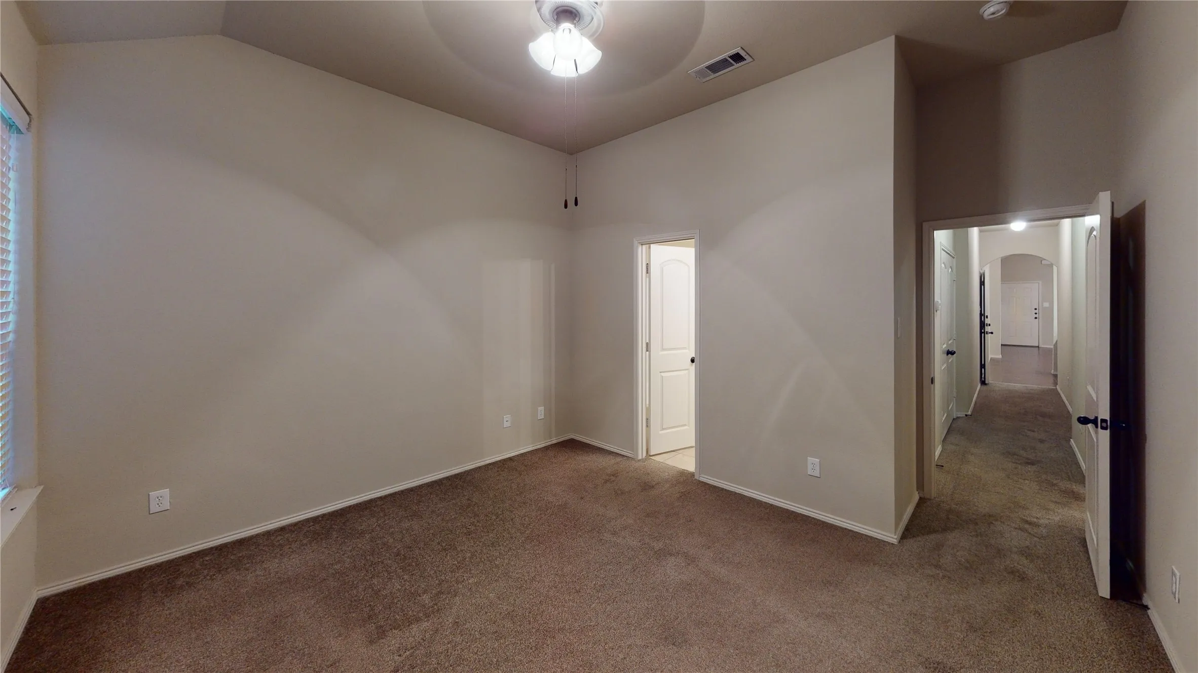 Unfurnished bedroom featuring carpet floors, a ceiling fan, arched walkways, and lofted ceiling