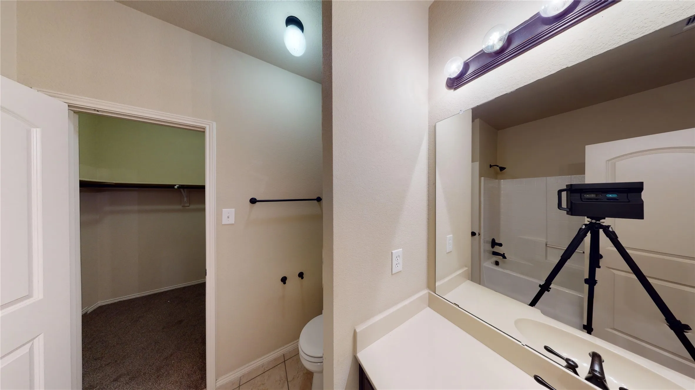 Bathroom with a spacious closet, vanity, light colored carpet, and shower / tub combination