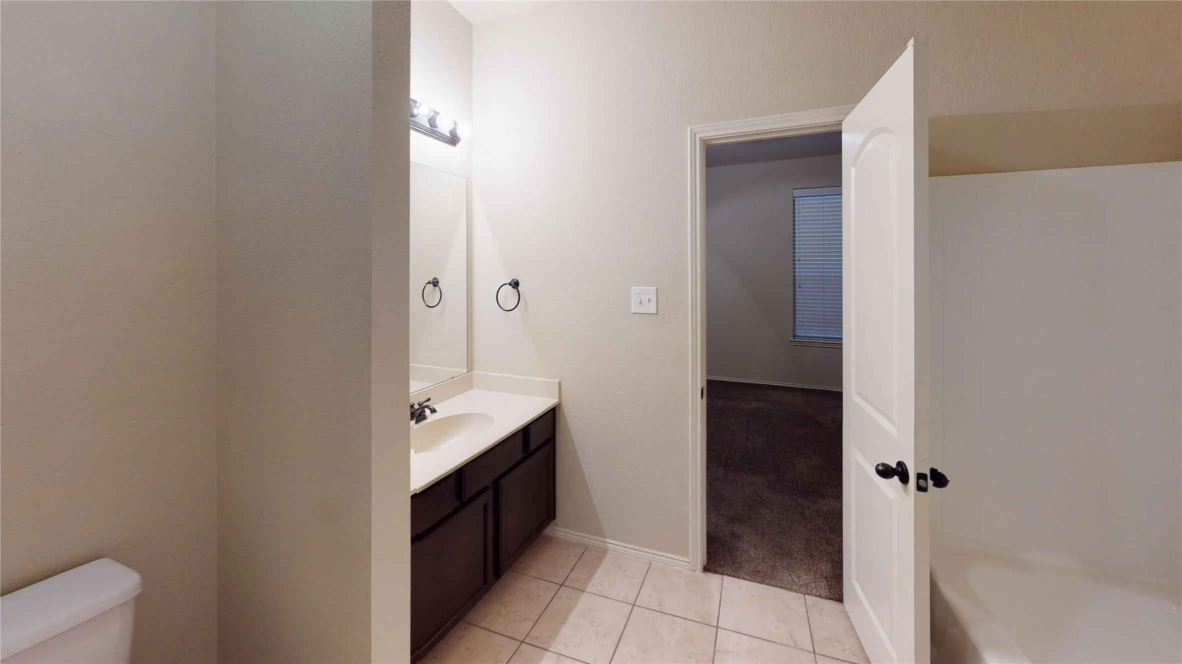 Full bath with vanity, a tub to relax in, light tile patterned floors, and light colored carpet