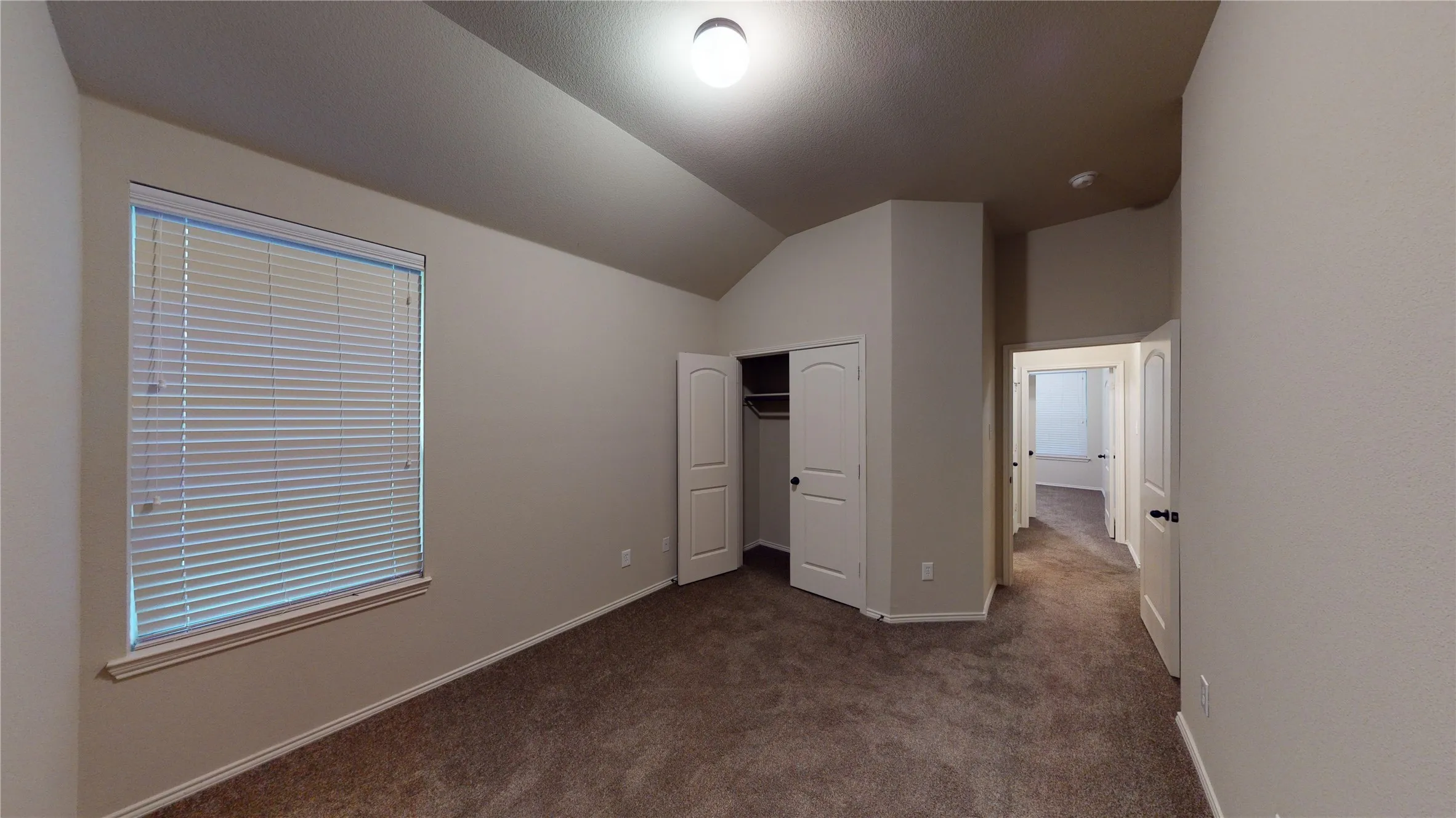 Unfurnished bedroom featuring dark colored carpet, vaulted ceiling, and a closet