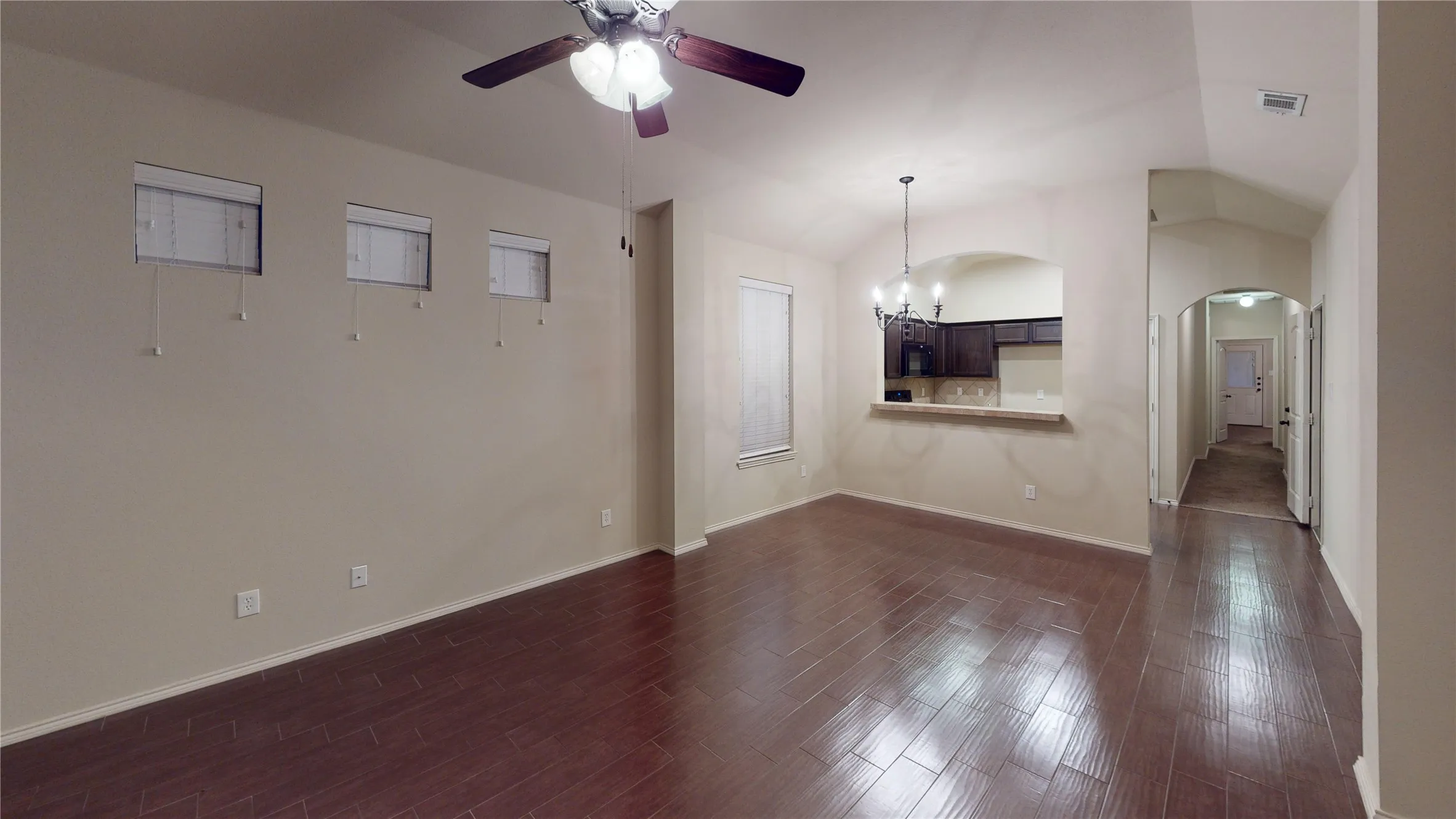 Spare room with a chandelier, a ceiling fan, lofted ceiling, dark wood finished floors, and arched walkways