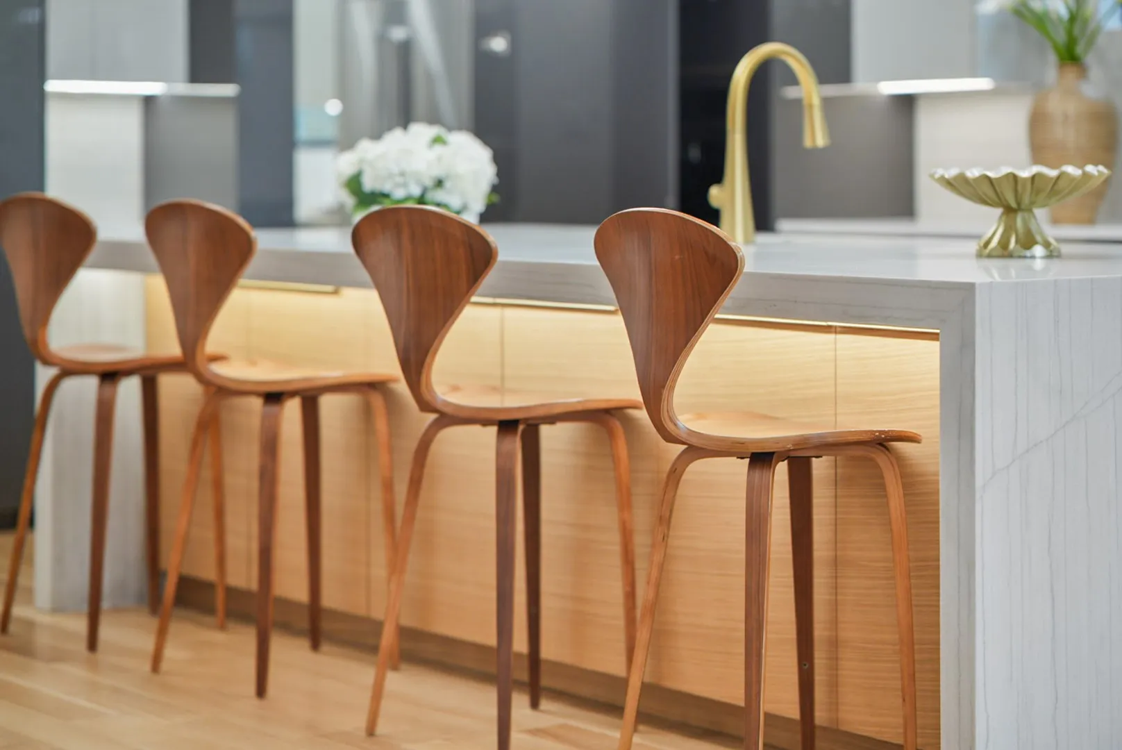 Waterfall-edge island with designer gold fixtures and under-cabinet lighting