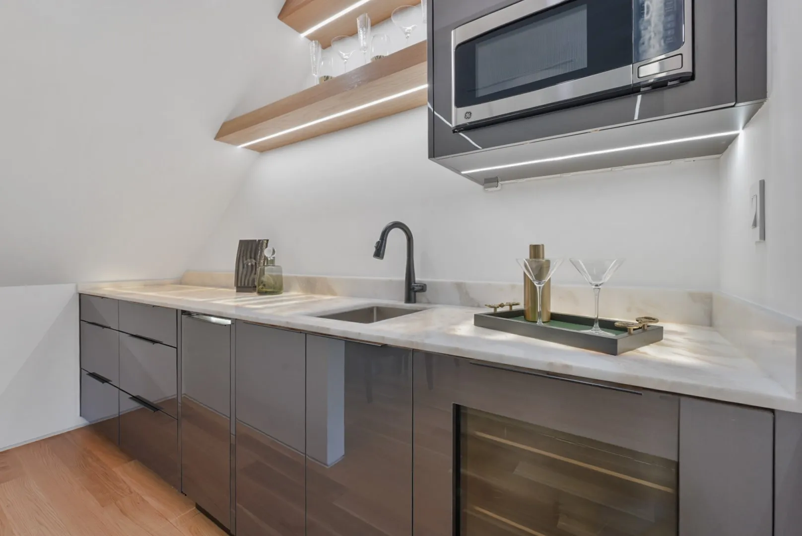 Entertainer's wet bar in stone and dark cabinetry serving the game level