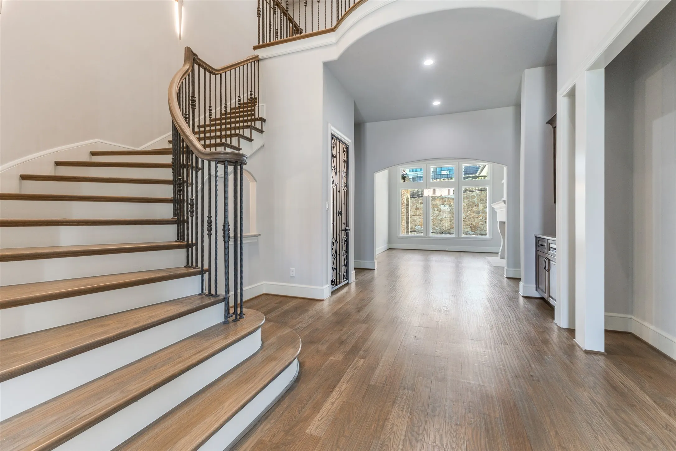Curved wooden primary staircase flanked by a wonderful space ready for any wine collection.