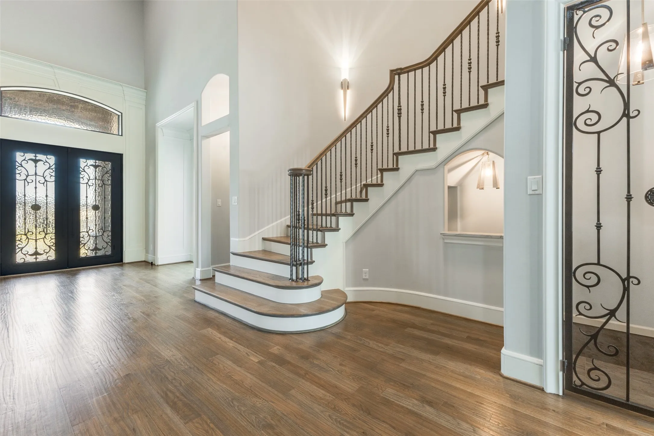 Entry featuring iron french doors, soaring ceilings, beautiful wood flooring, and amazing detail.