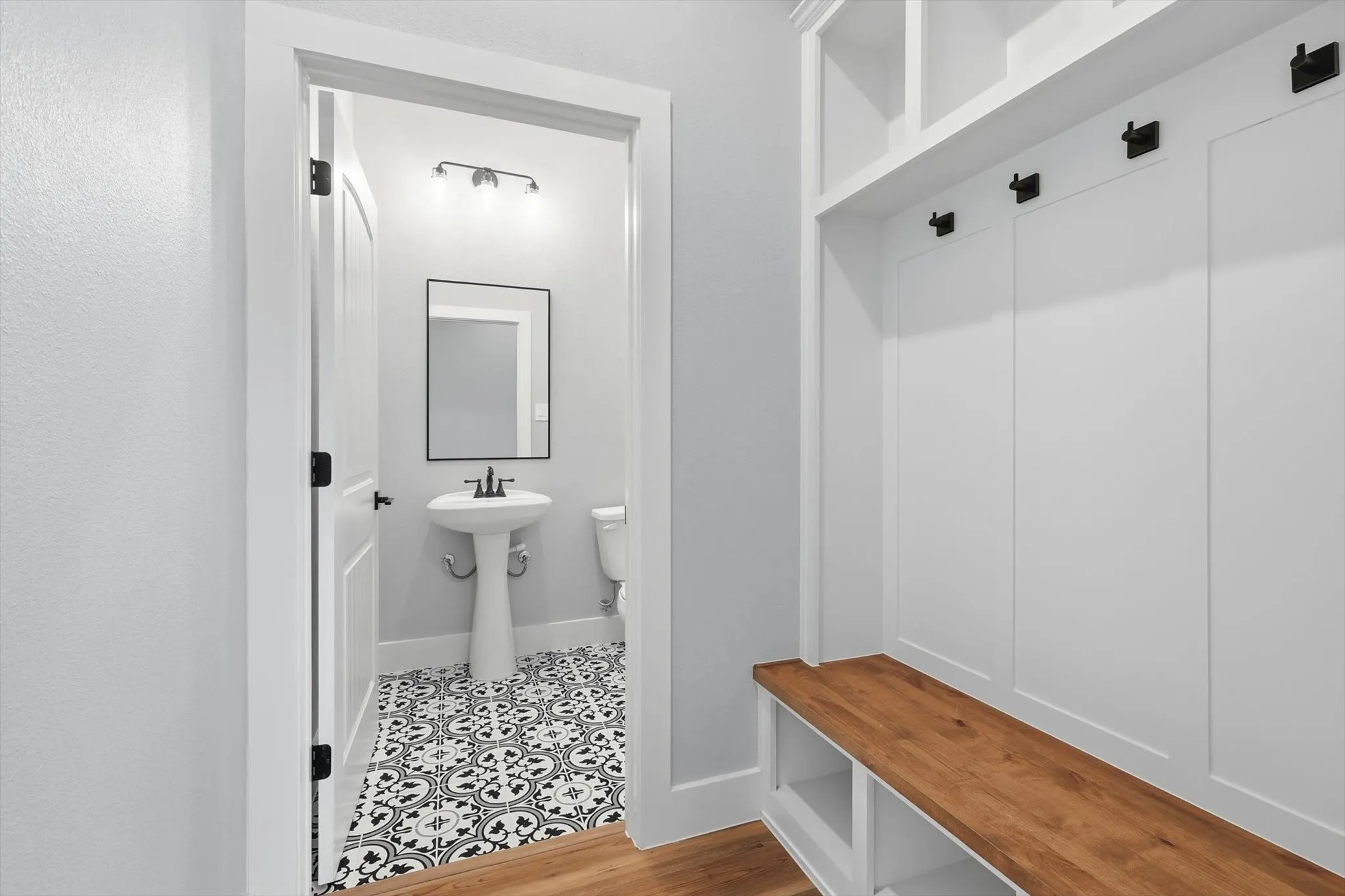 Drop-zone perfection. Built-in mudroom bench + cubbies + hooks with warm wood accents—plus a stylish powder bath nearby for everyday convenience.