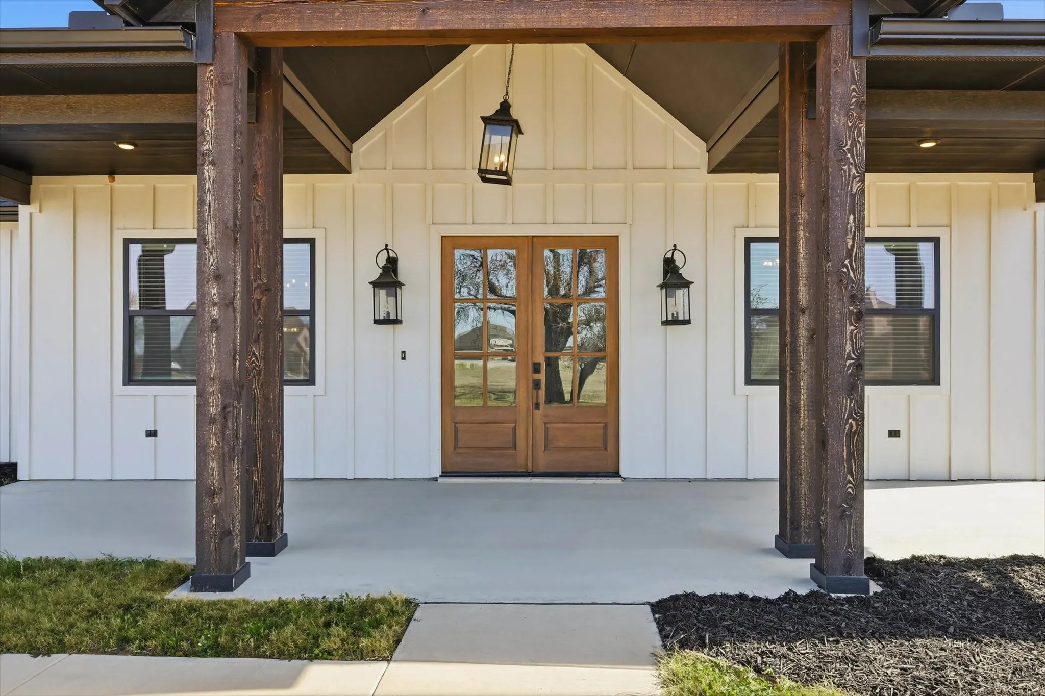 The porch you’ve been dreaming about. Oversized stained posts, warm lighting, and gorgeous double doors create a welcoming entry that feels upscale, cozy, and built for “sit-a-while” evenings.