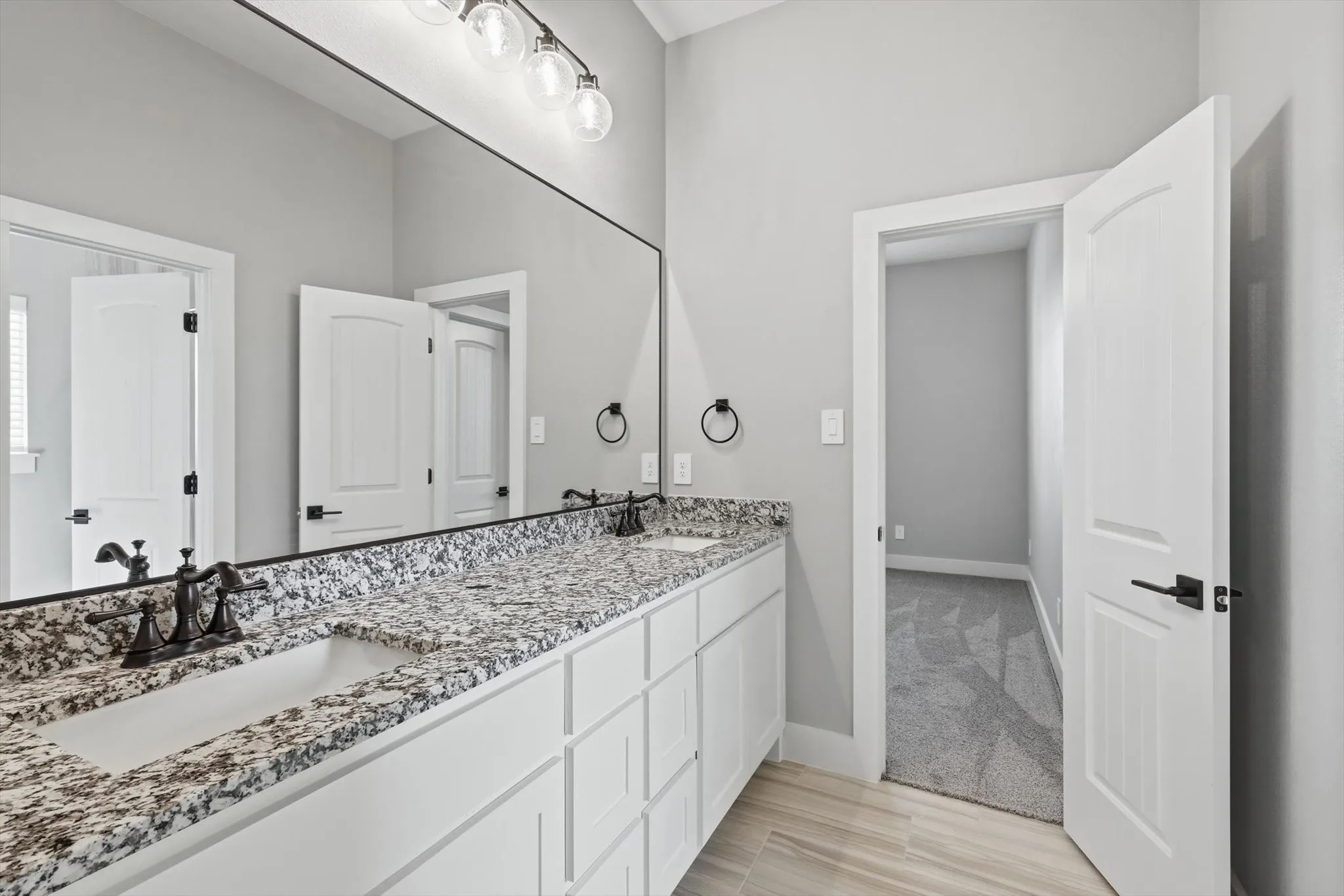 Clean, modern secondary bath. Granite-style counters, double-sink vanity, oversized mirror, and updated lighting—made for busy mornings.