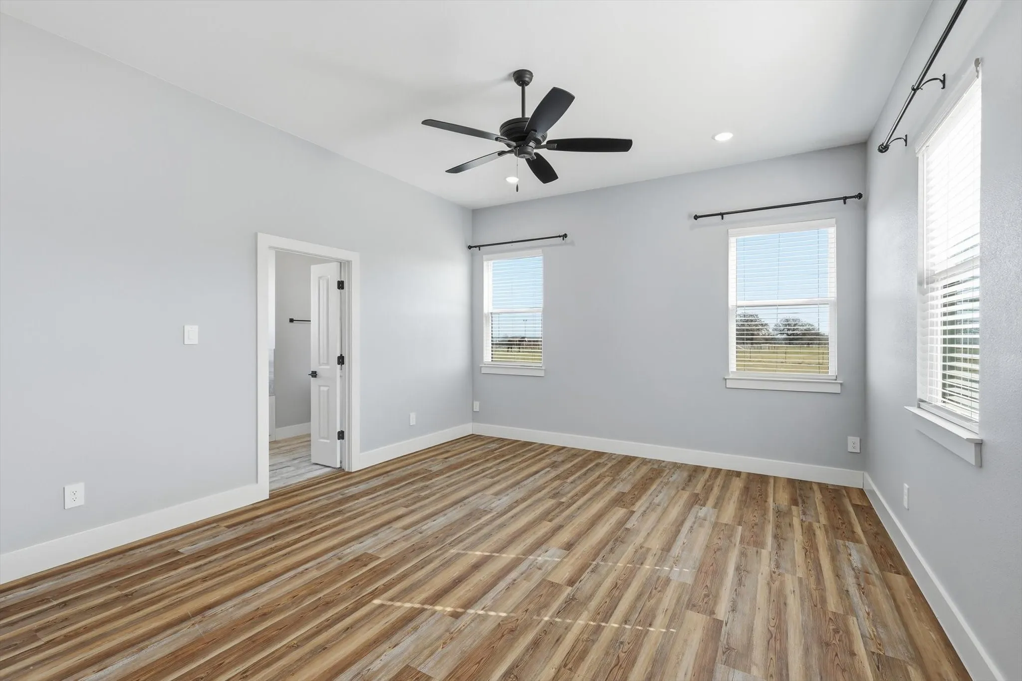 A true primary retreat. Spacious bedroom with luxury vinyl plank floors, modern ceiling fan, and windows that bring in natural light and peaceful views.