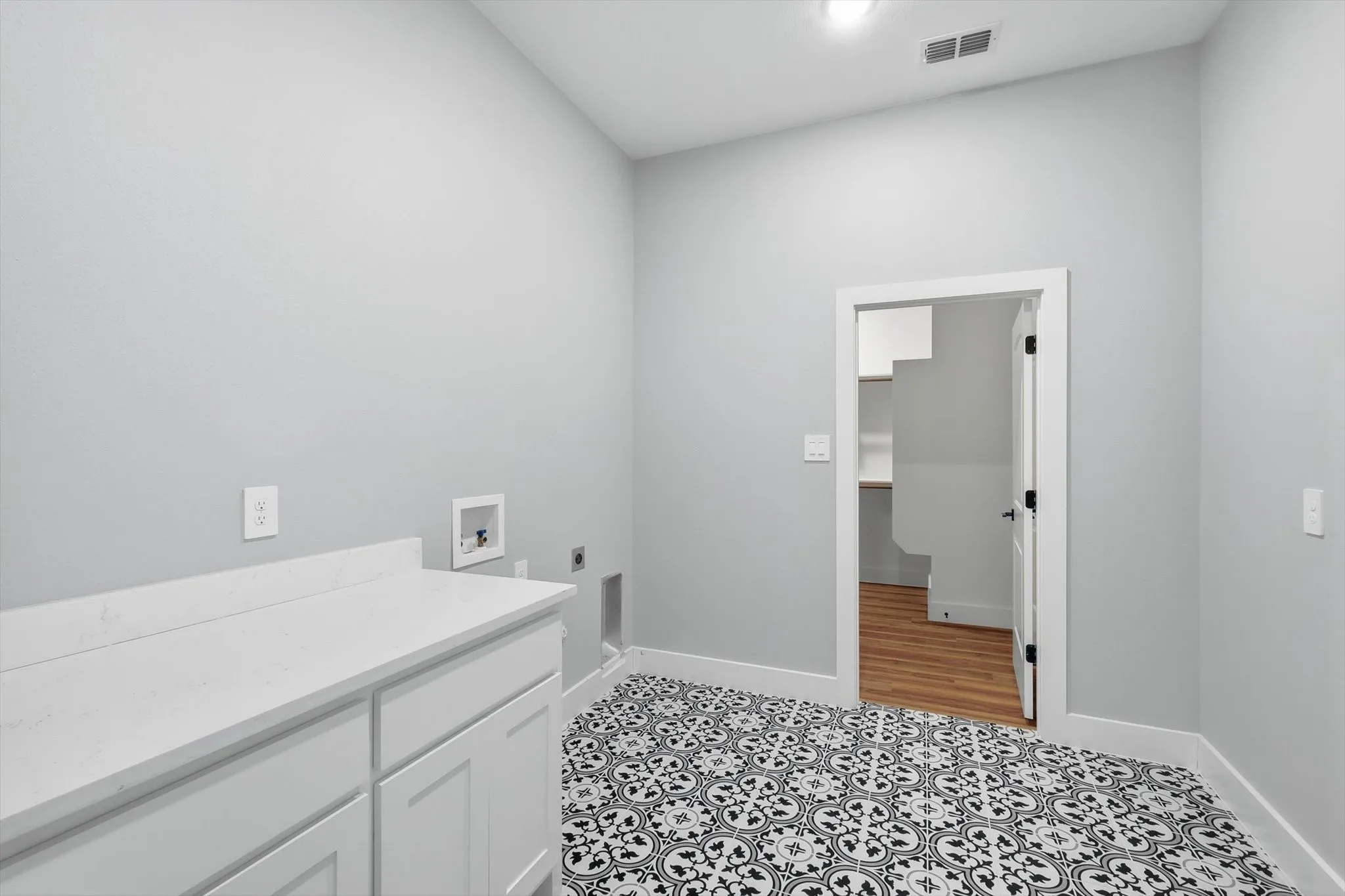 Laundry room you’ll actually love. Dedicated space with counter area, storage, and eye-catching patterned flooring—clean, bright, and functional.