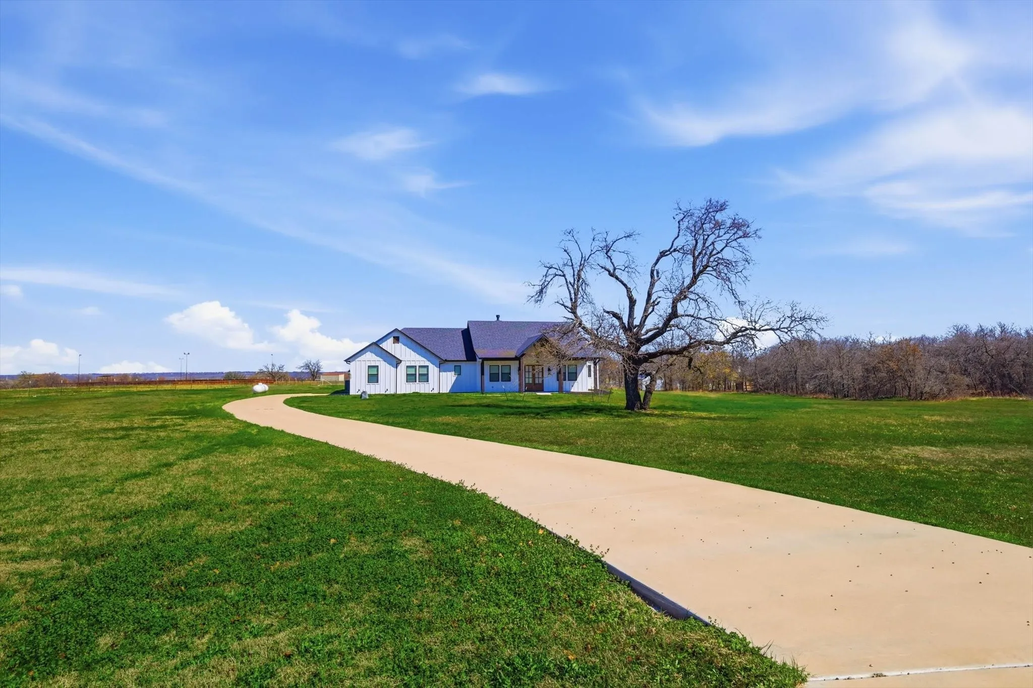 A graceful curved driveway leads to this stunning modern farmhouse, beautifully positioned on an expansive homesite with scenic views in every direction. Clean lines, timeless finishes, and a picturesque setting come together to create a front elevation that feels both elegant and welcoming.