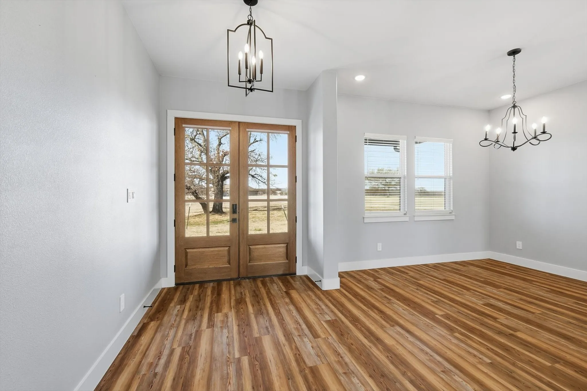 A grand welcome. Gorgeous double wood doors, warm luxury vinyl plank floors, and statement lighting create a bright, upscale entry that instantly feels like home.