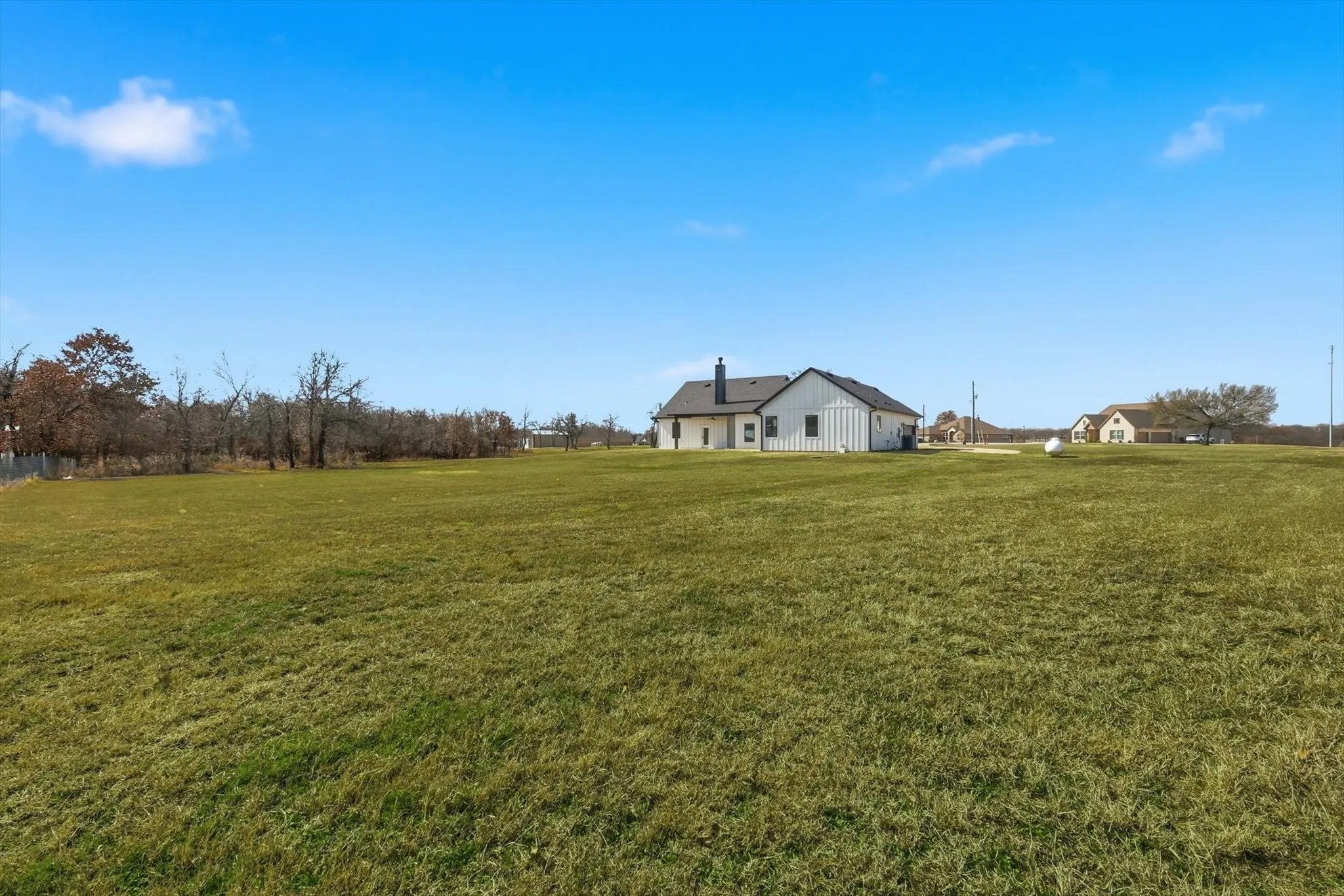 Open yard with natural borders and partial fencing. Expansive grass space with treeline views—ideal for enjoying quiet evenings, outdoor hobbies, or letting the dogs run.
