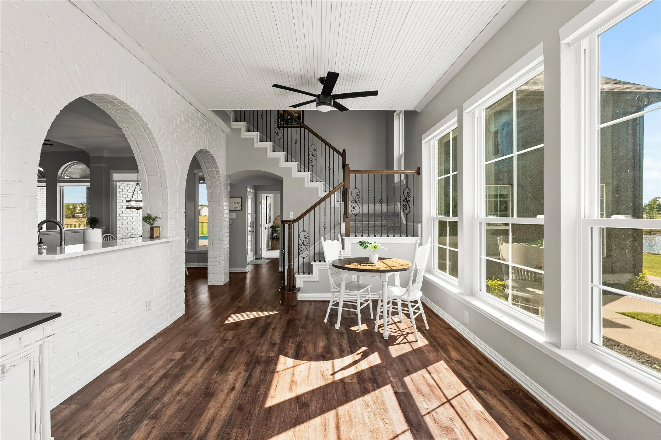 Multi-use space featuring arched walkways, plenty of natural light, dark wood finished floors, stairs, and brick wall