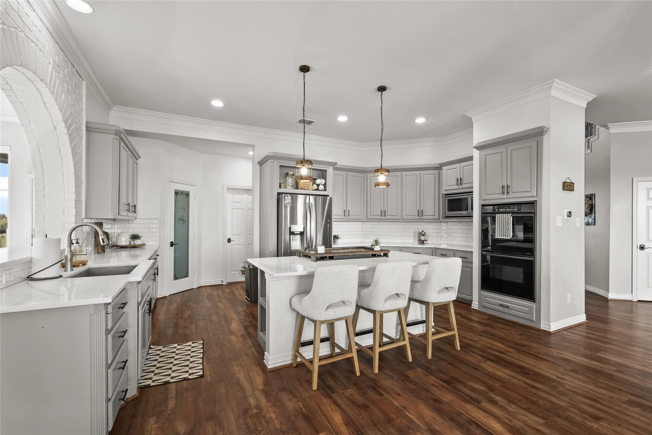 Kitchen with gray cabinets, a center island, decorative backsplash, appliances with stainless steel finishes, and hanging light fixtures