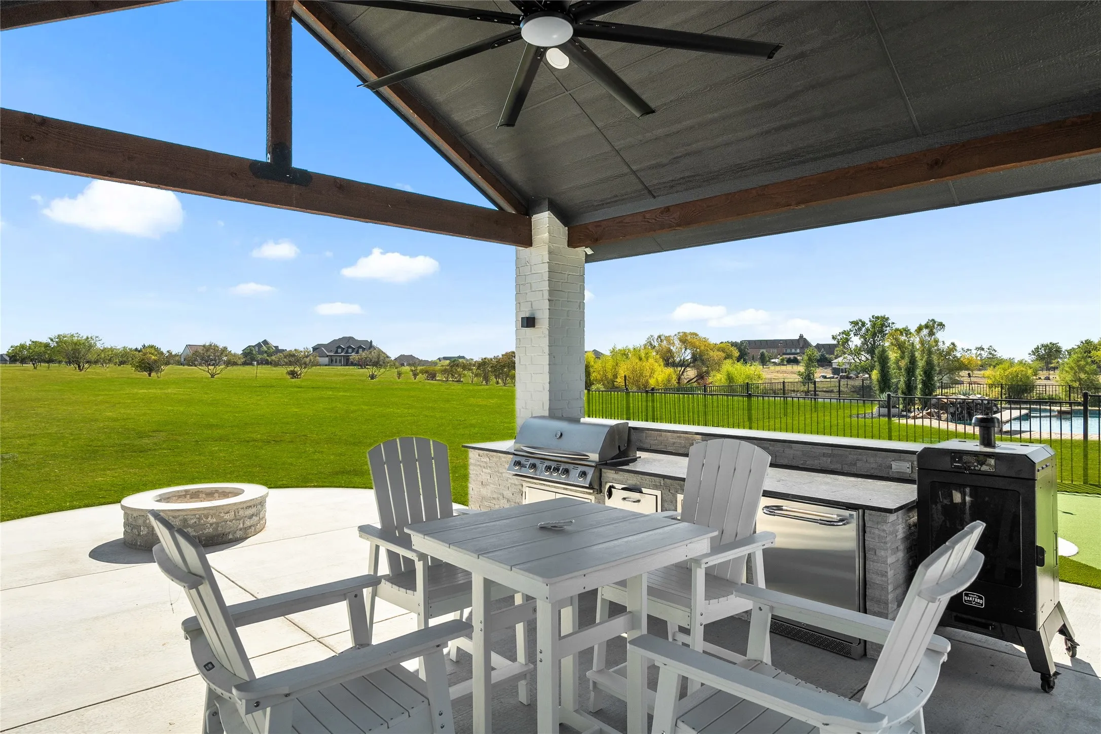 View of patio / terrace with exterior kitchen, a ceiling fan, outdoor dining space, and an outdoor fire pit