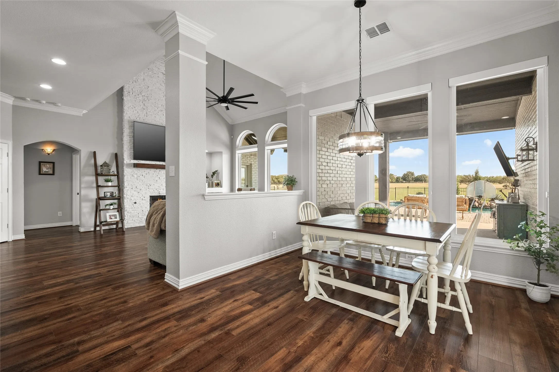 Dining room featuring crown molding, a fireplace, dark wood finished floors, ceiling fan, and a chandelier