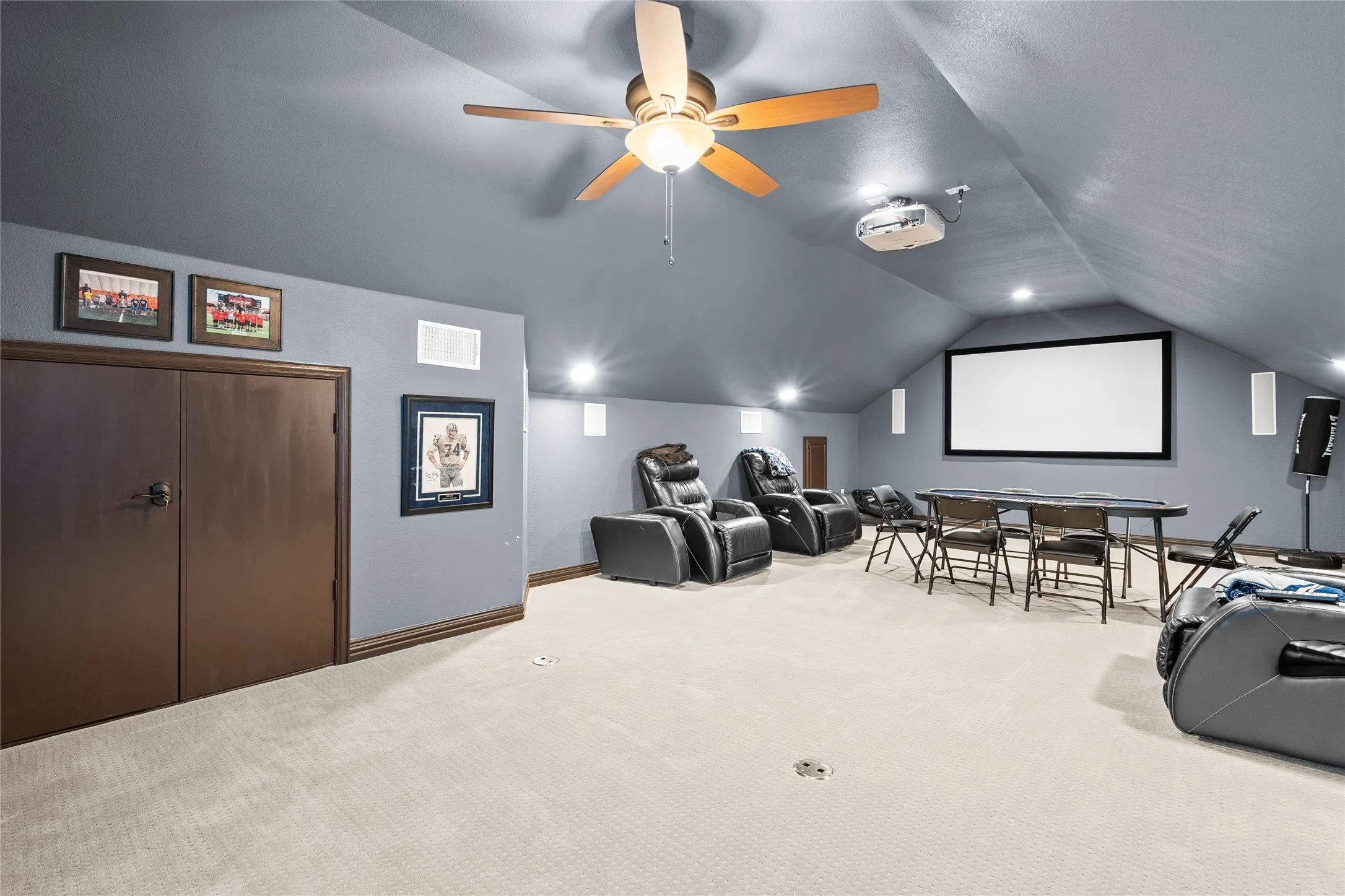 Carpeted cinema room with ceiling fan and lofted ceiling