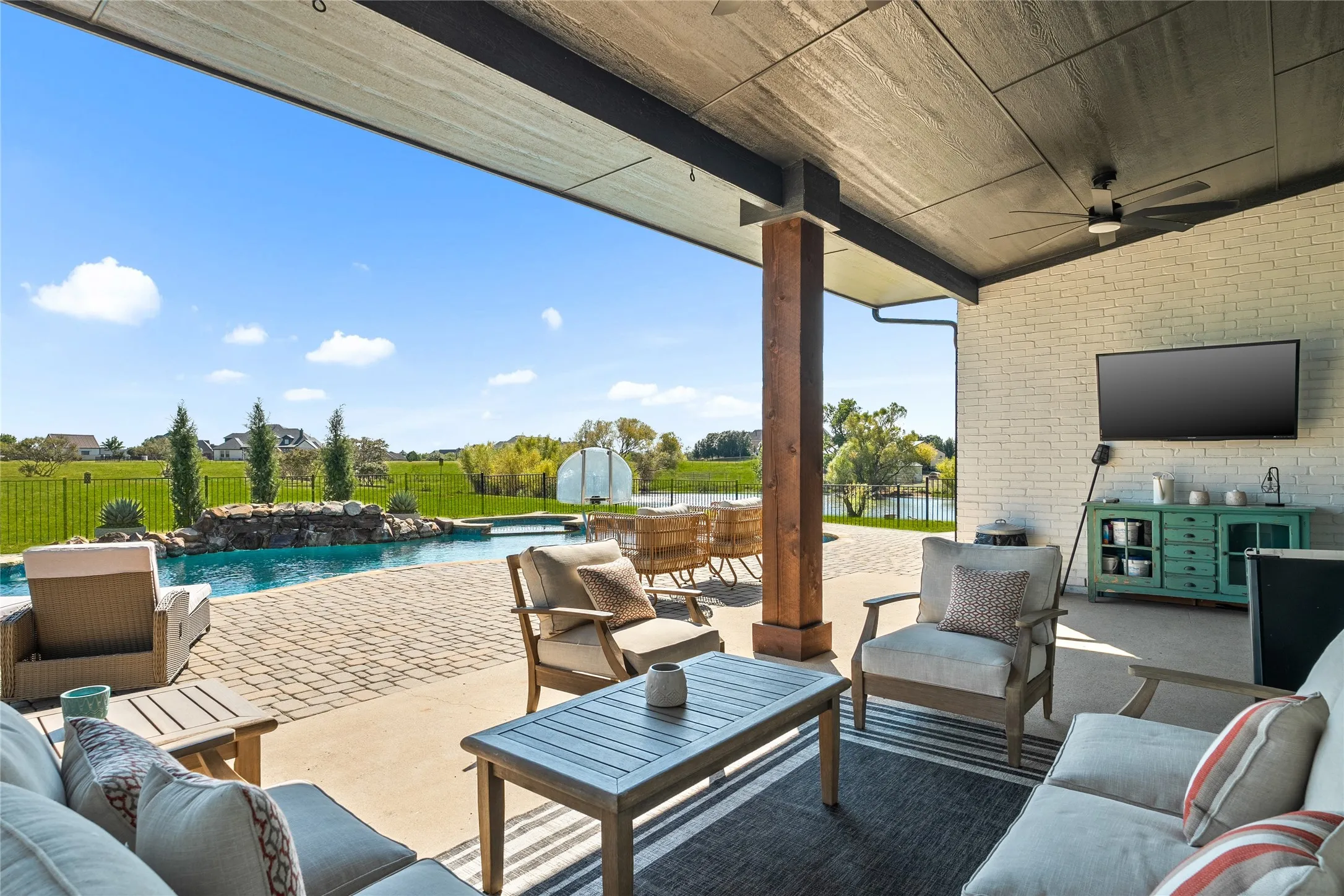 Fenced backyard with an outdoor hangout area, a patio area, ceiling fan, and a pool with connected hot tub