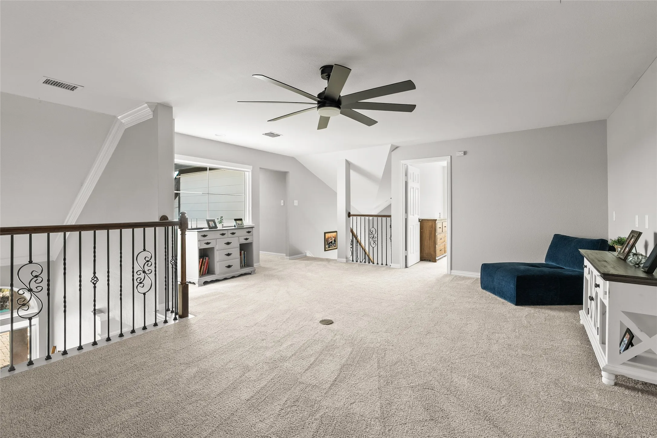 Sitting room featuring light carpet, ceiling fan, and an upstairs landing