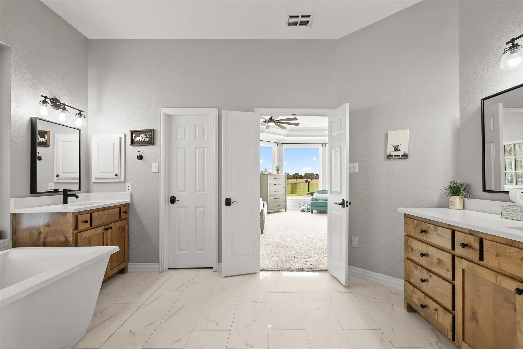 Bathroom with vanity, light marble finish floors, connected bathroom, ceiling fan, and a freestanding bath