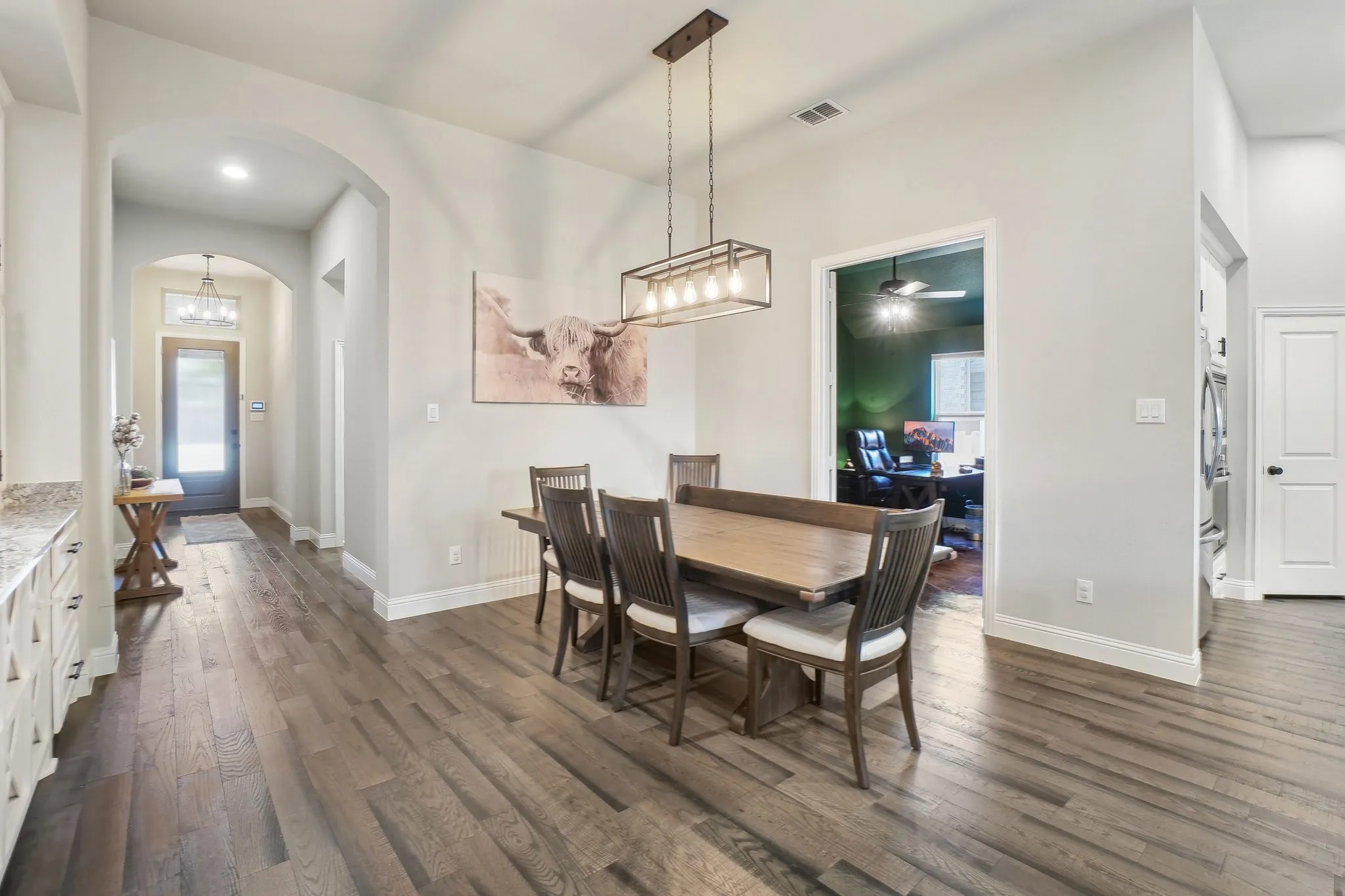 Dining room with dark wood-style floors, arched walkways, and suspended lighting