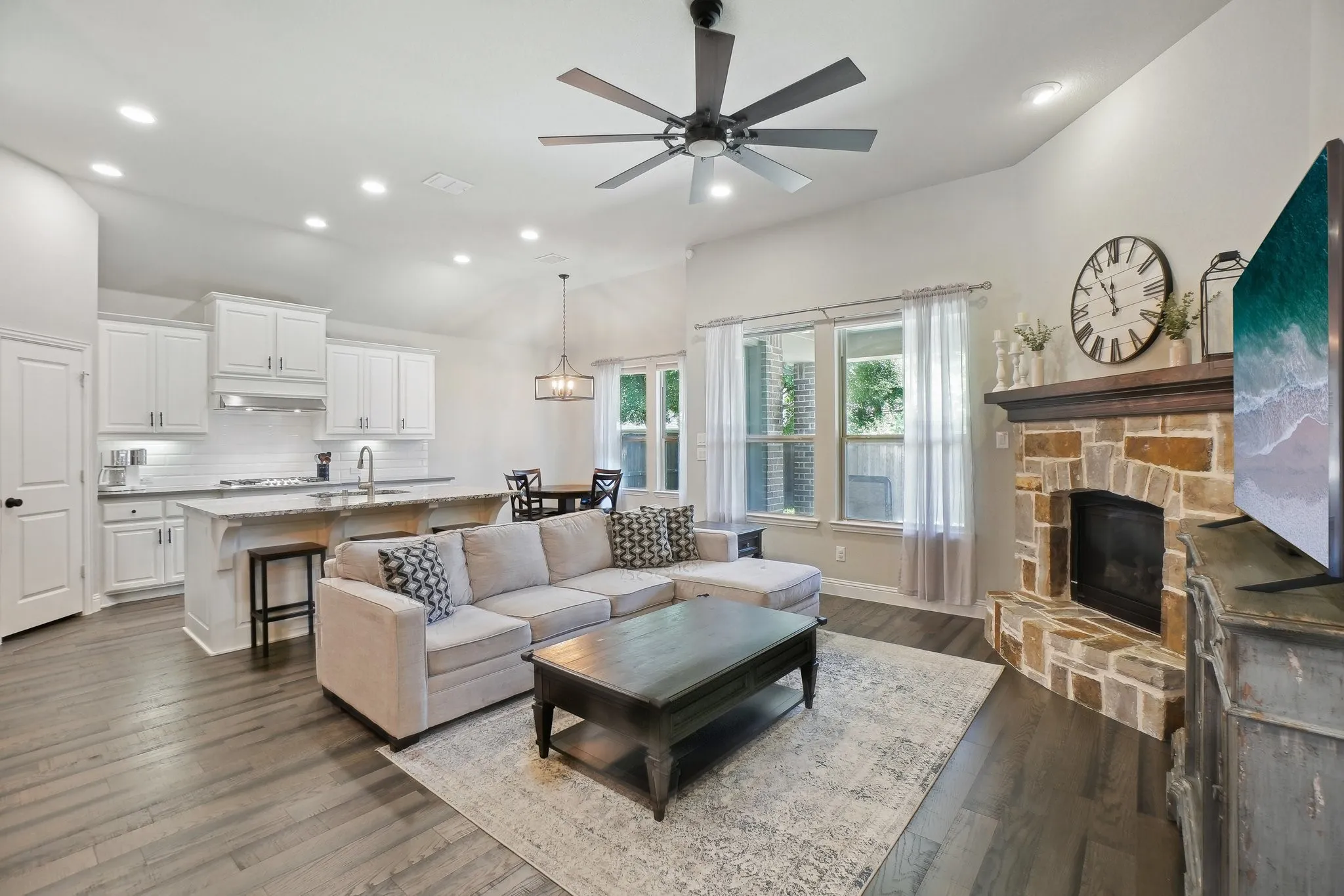 Living area featuring a ceiling fan, recessed lighting, dark wood finished floors, a fireplace, and vaulted ceiling