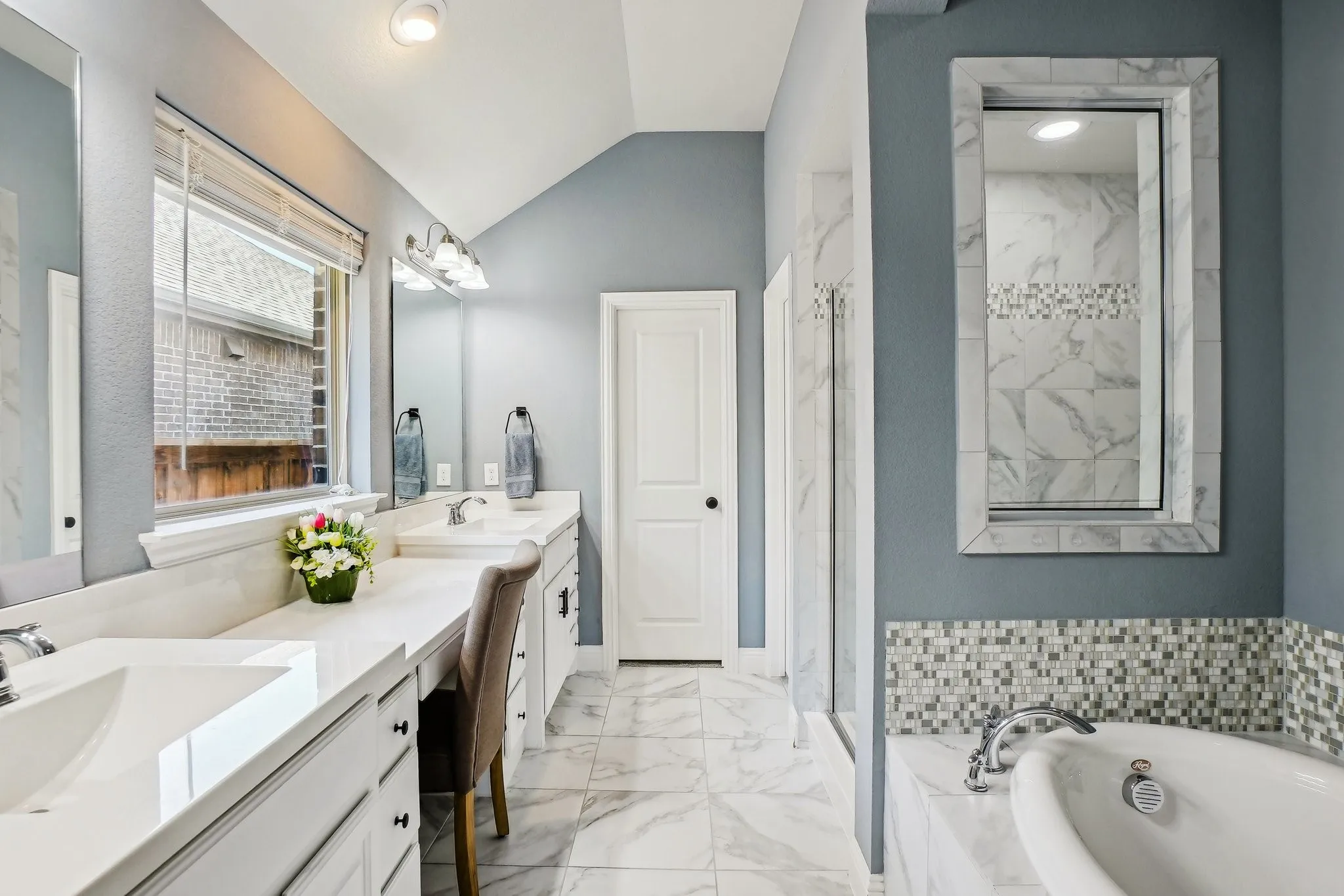 Bathroom with light marble finish floors, vaulted ceiling, double vanity, a bath, and a marble finish shower