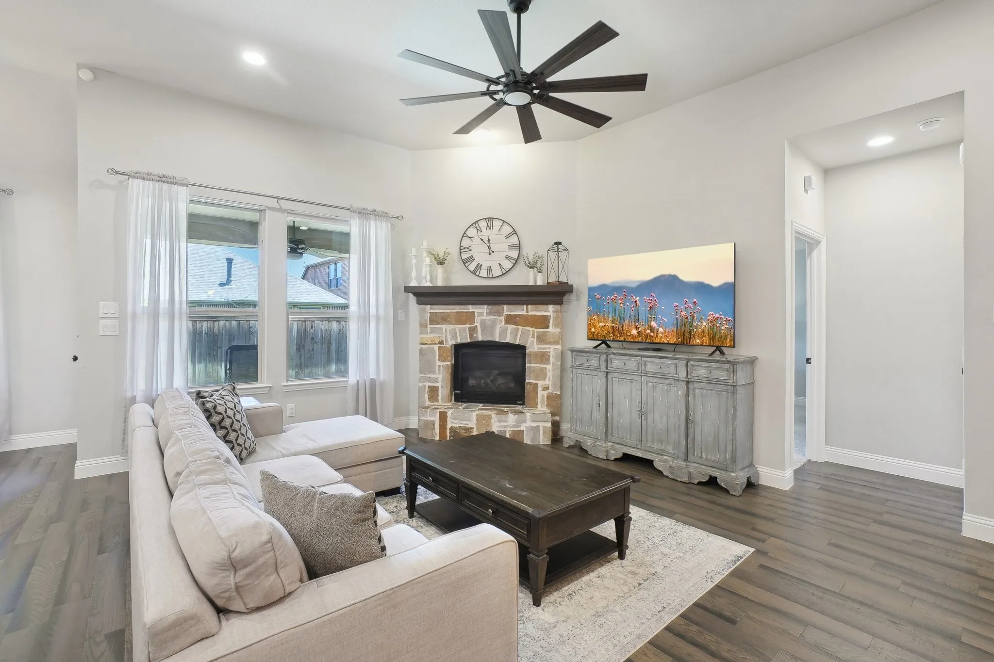 Living area with a ceiling fan, dark wood finished floors, recessed lighting, and a stone fireplace