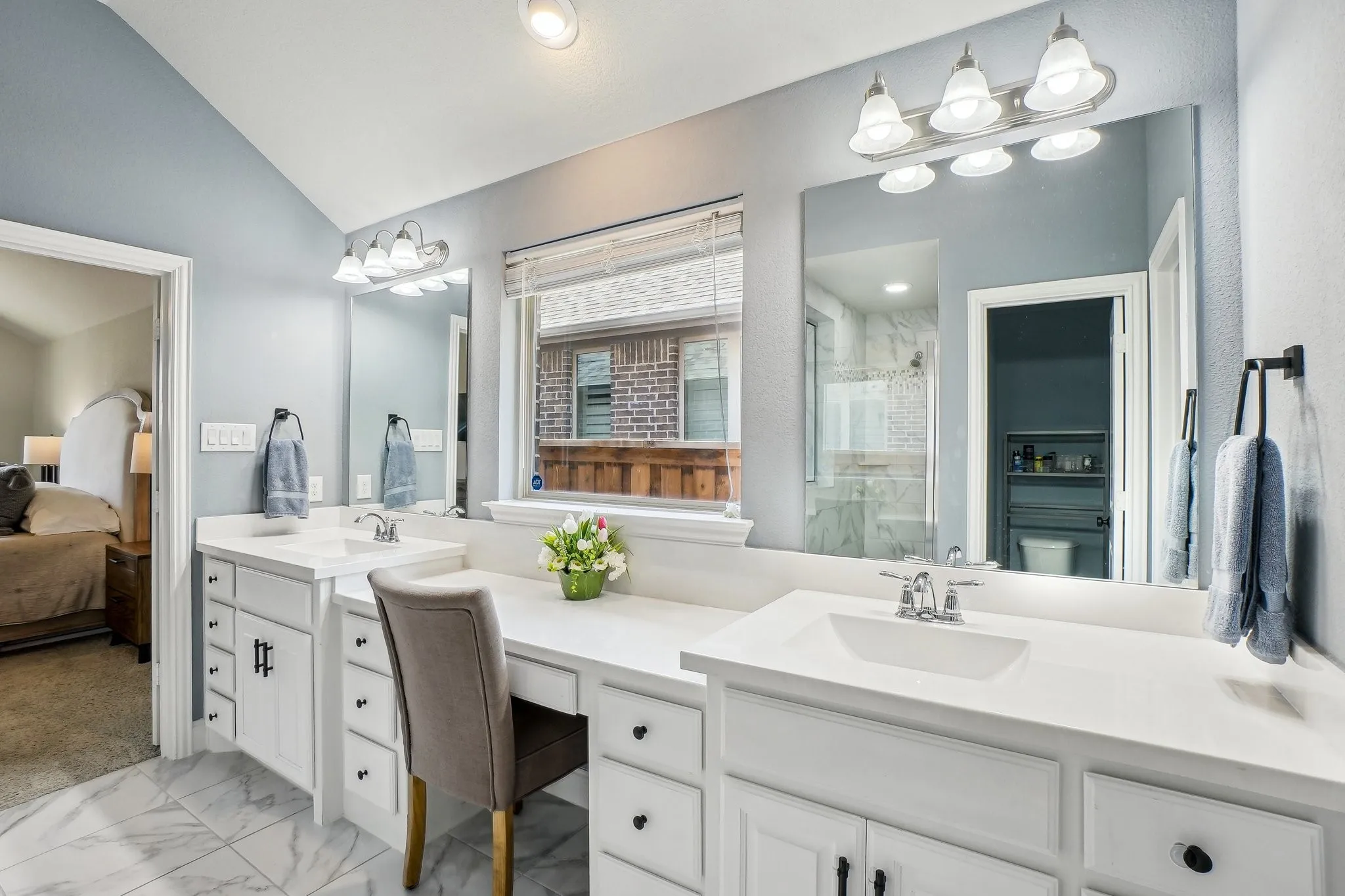 Bathroom featuring two vanities, double vanity, connected bathroom, a stall shower, and lofted ceiling