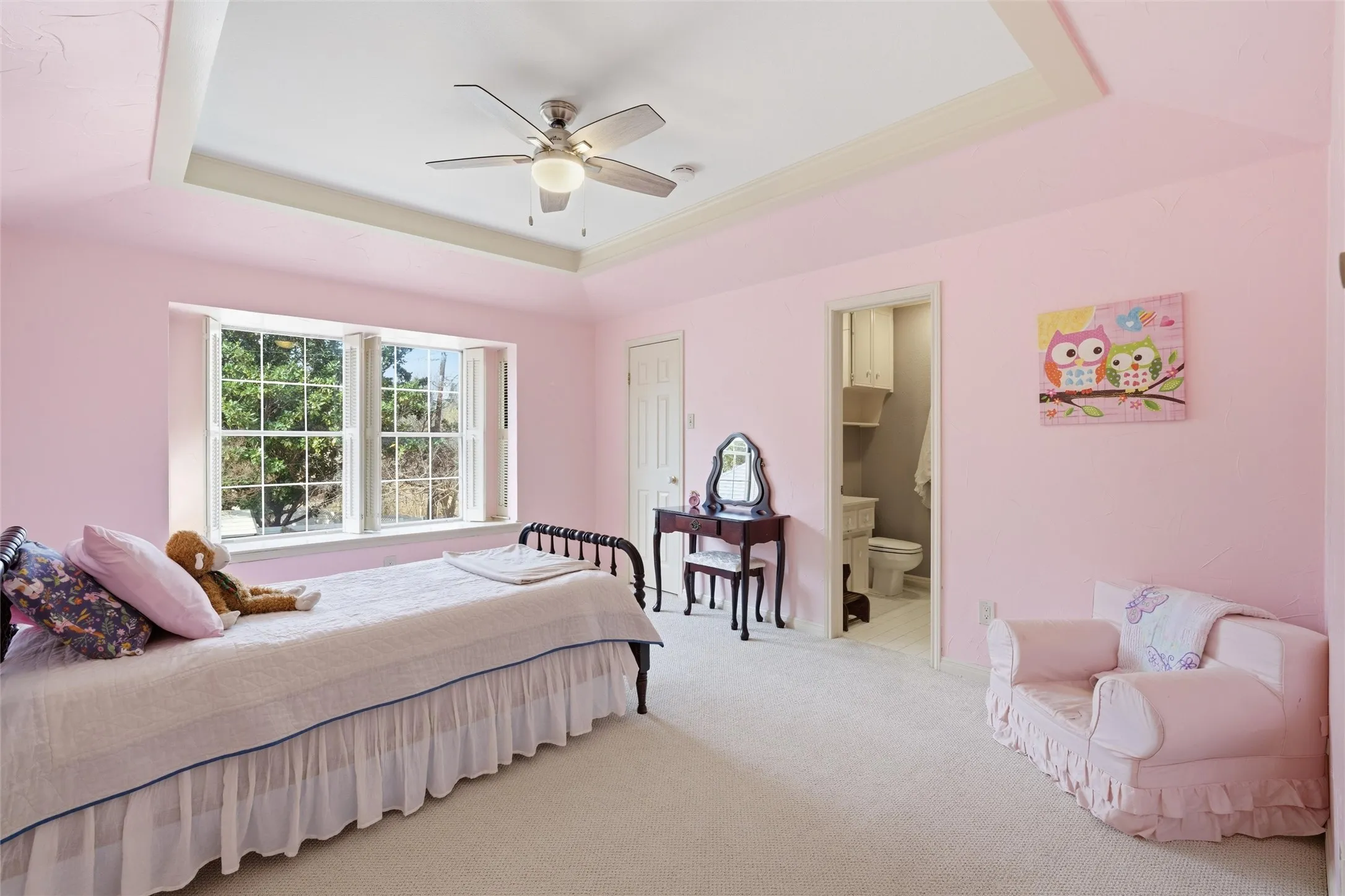 Carpeted bedroom with a tray ceiling, a ceiling fan, and ensuite bath