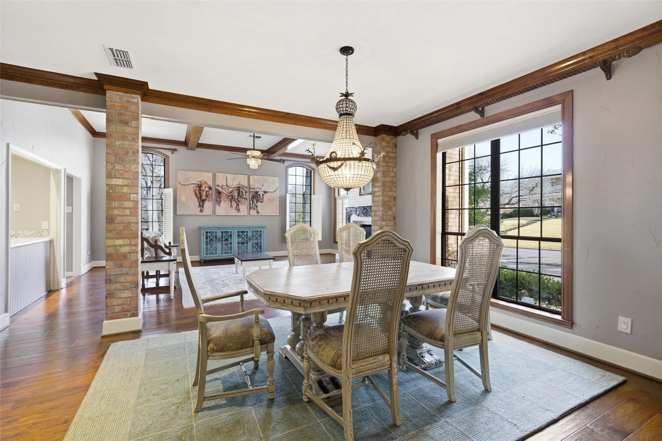 Dining room with dark wood finished floors, beam ceiling, a chandelier, ceiling fan, and ornamental molding