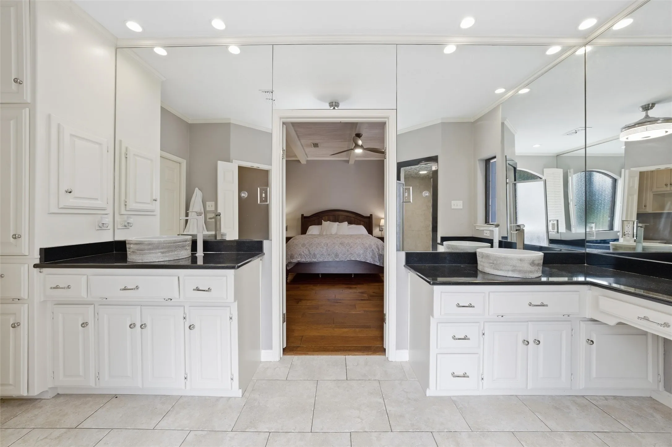 Ensuite bathroom featuring two vanities, crown molding, recessed lighting, light tile patterned flooring, and ceiling fan