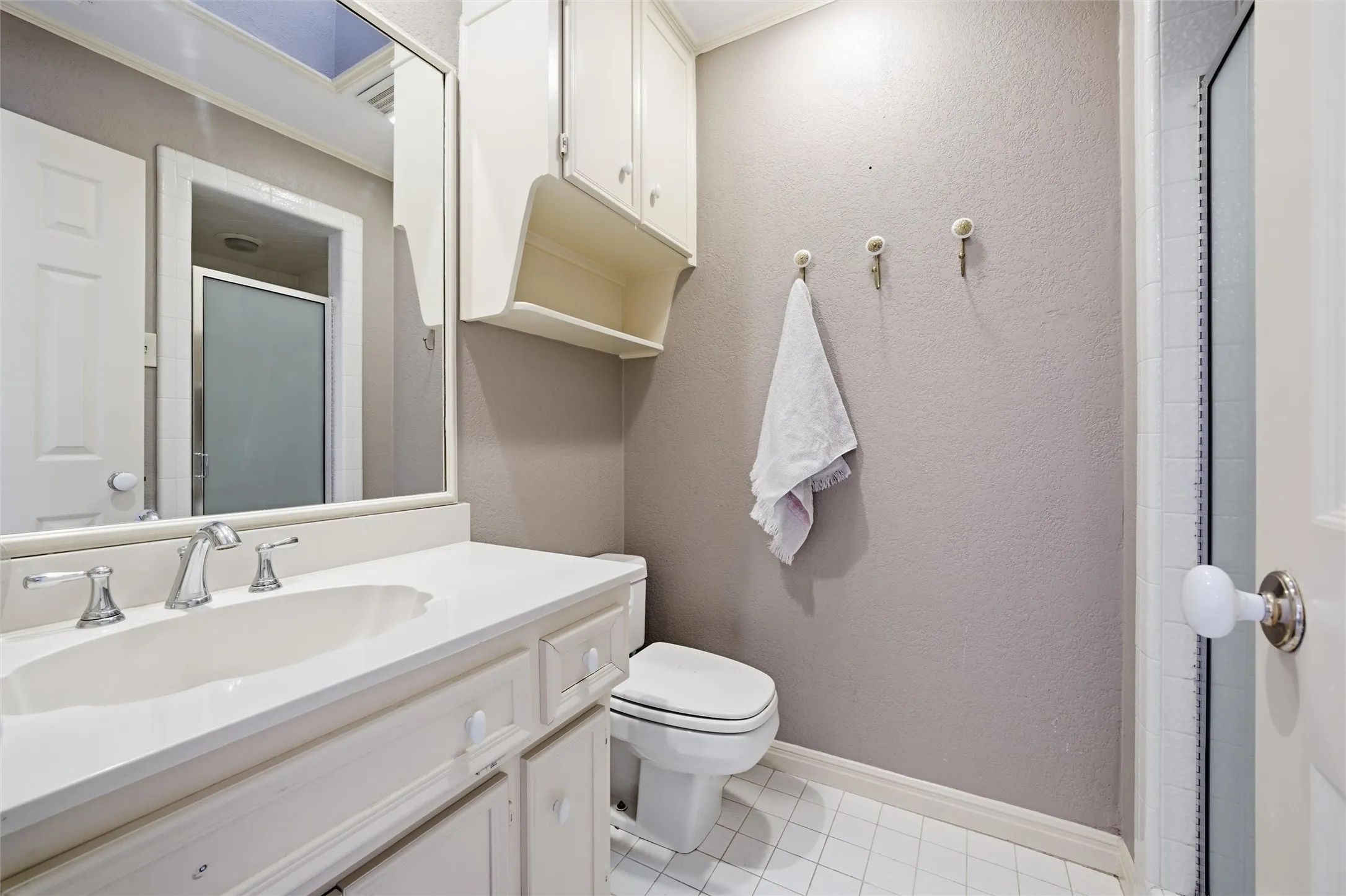 Bathroom with a stall shower, vanity, light tile patterned floors, and a textured wall