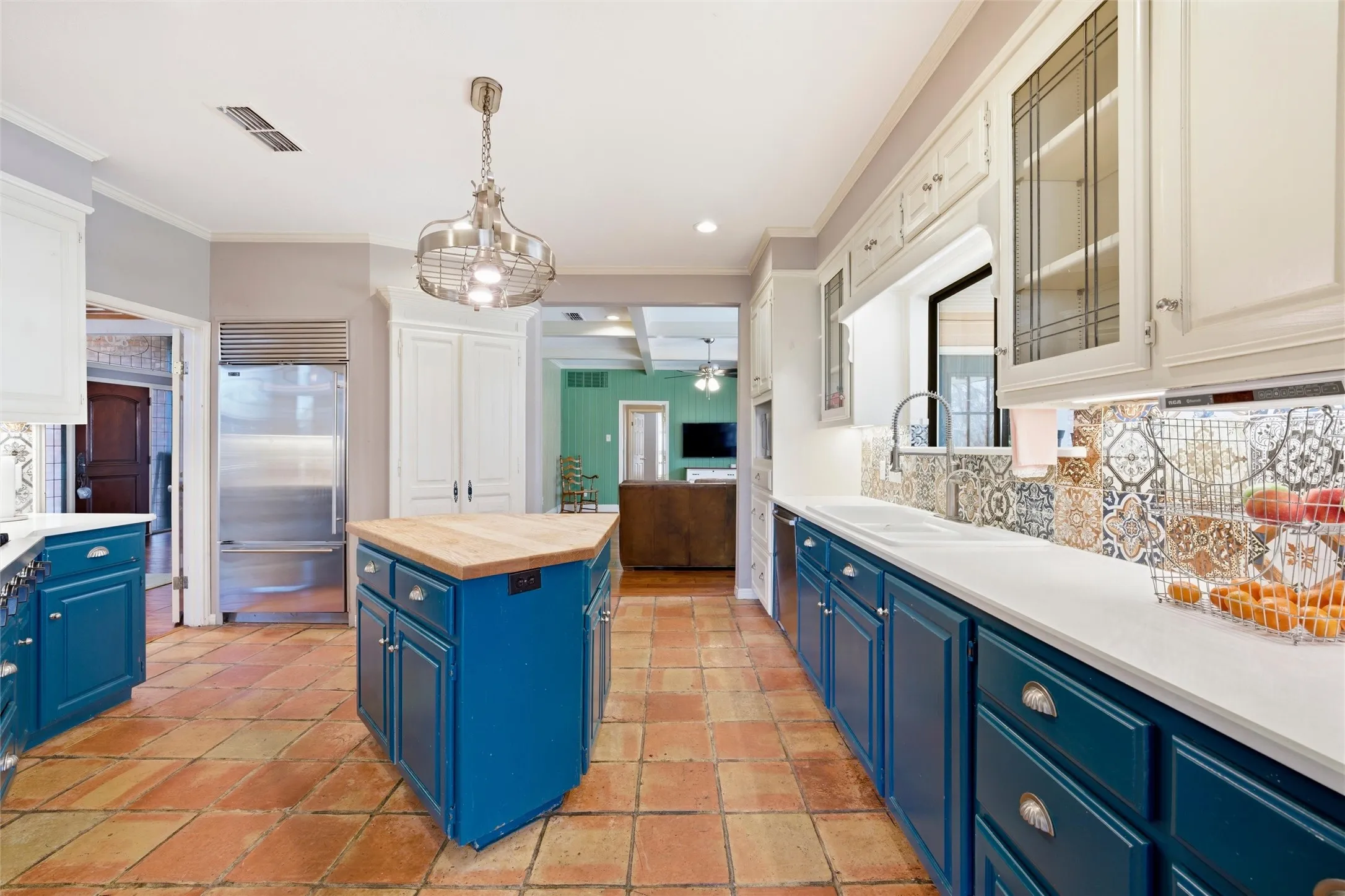 Two tone kitchen with a center island, stainless steel appliances, glass fronted cabinets, crown molding, and two tone cabinets