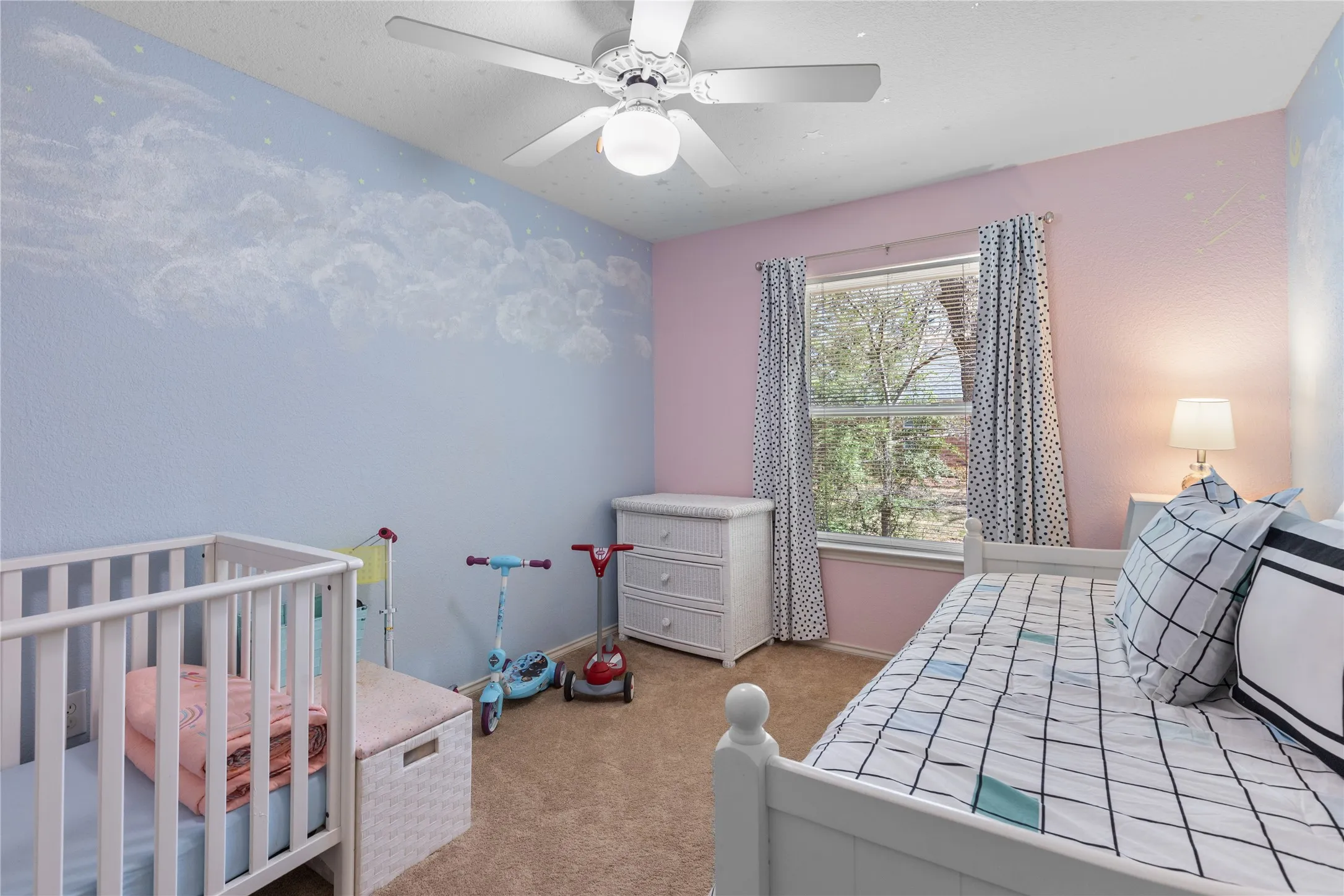 Bedroom featuring light carpet, a crib, and a ceiling fan