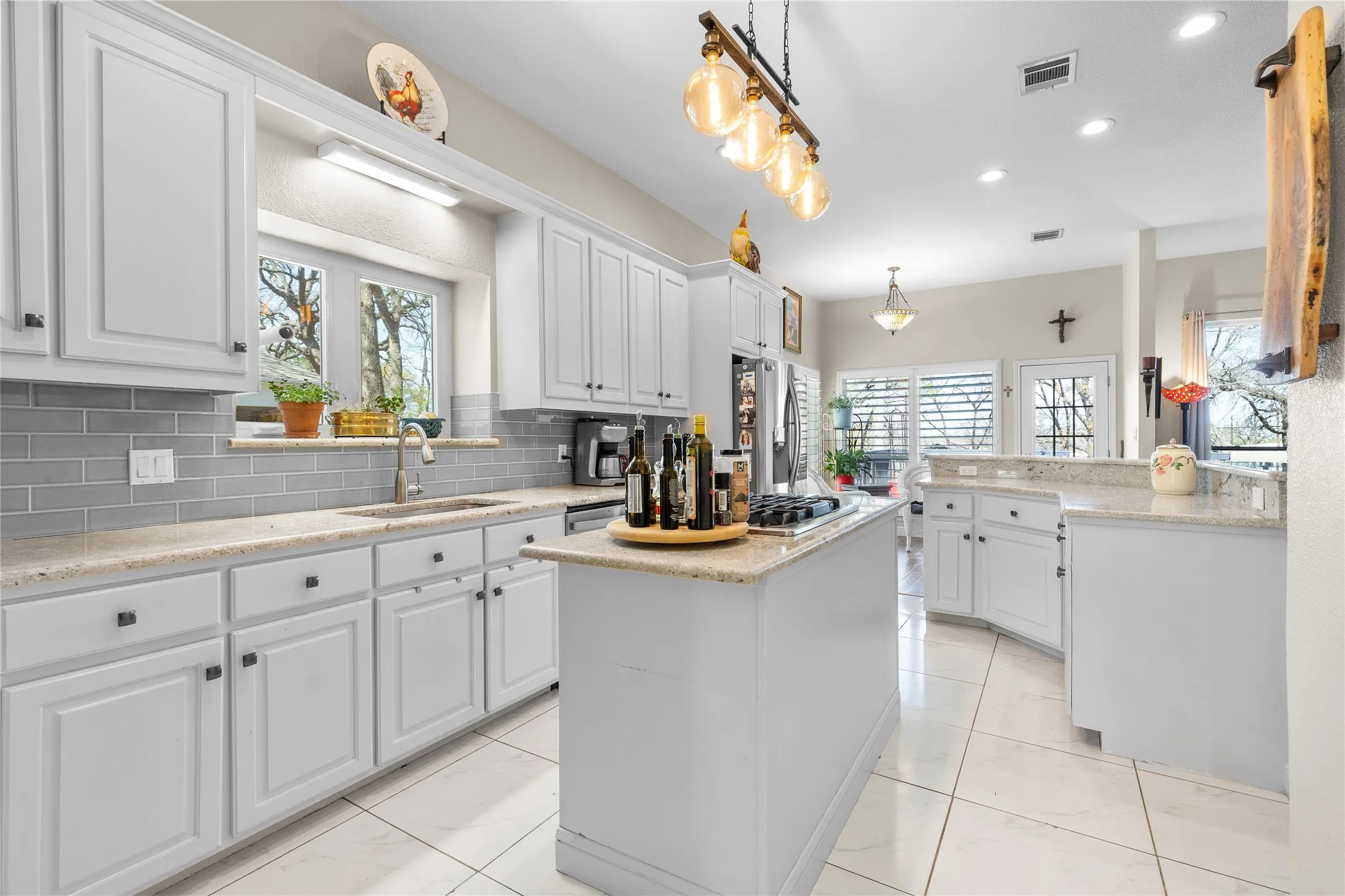 Kitchen featuring white cabinets, light stone counters, a center island, and a peninsula