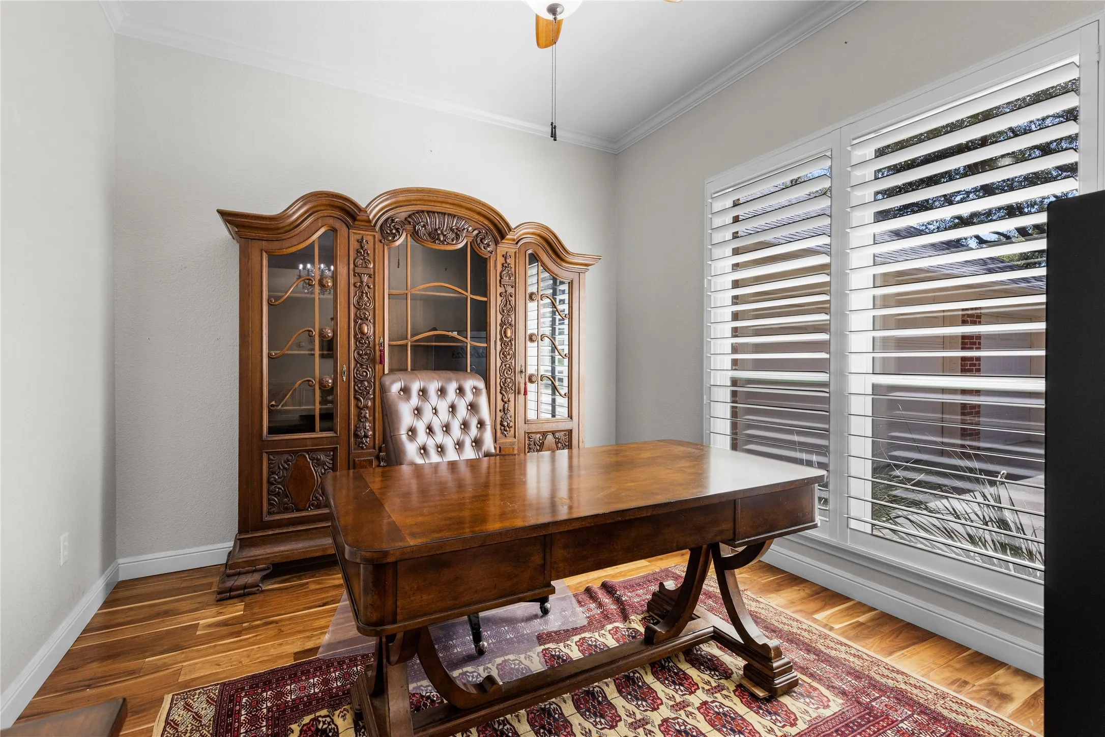 Office with ornamental molding, could also be living room wood finished floors, and ceiling fan