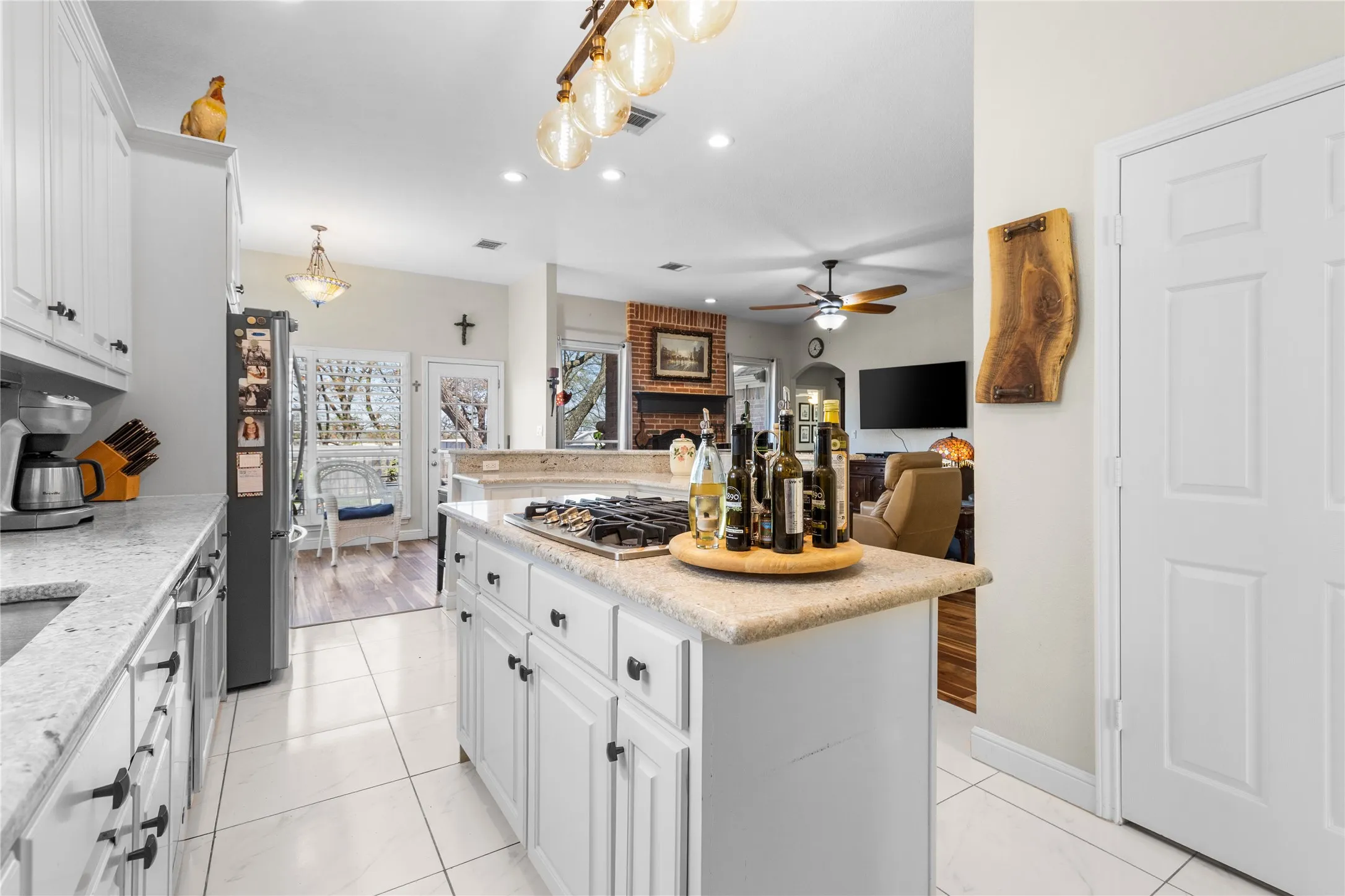 Kitchen featuring white cabinets, open floor plan, light stone countertops, stainless steel appliances, and ceiling fan